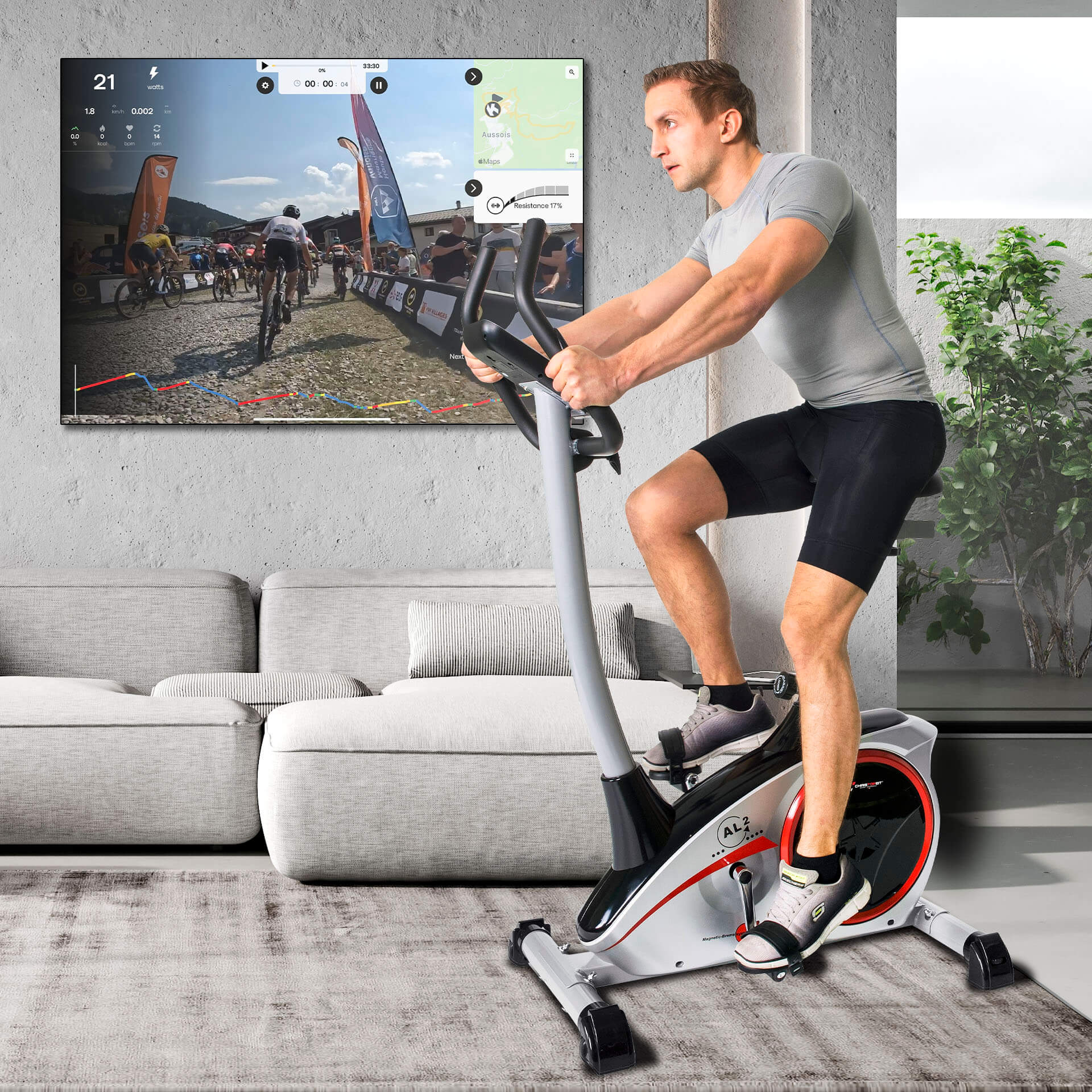 Mann fährt auf einem Heimtrainer und schaut sich ein Rennen auf dem Bildschirm an. Der Raum hat ein Sofa, einen Teppich und eine Pflanze.