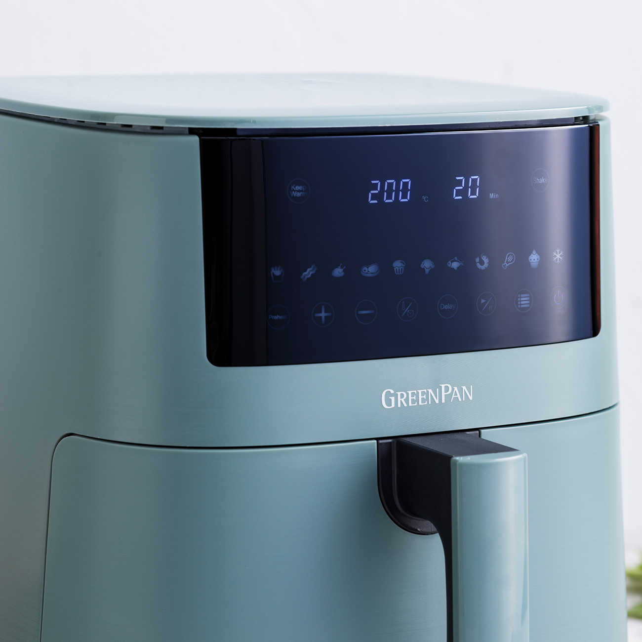 Ein türkisfarbener GreenPan-Heißluftfritteuse zeigt 200 °C und 20 Minuten auf dem Display. Sie hat einen Griff und verschiedene Kochvoreinstellungen.
