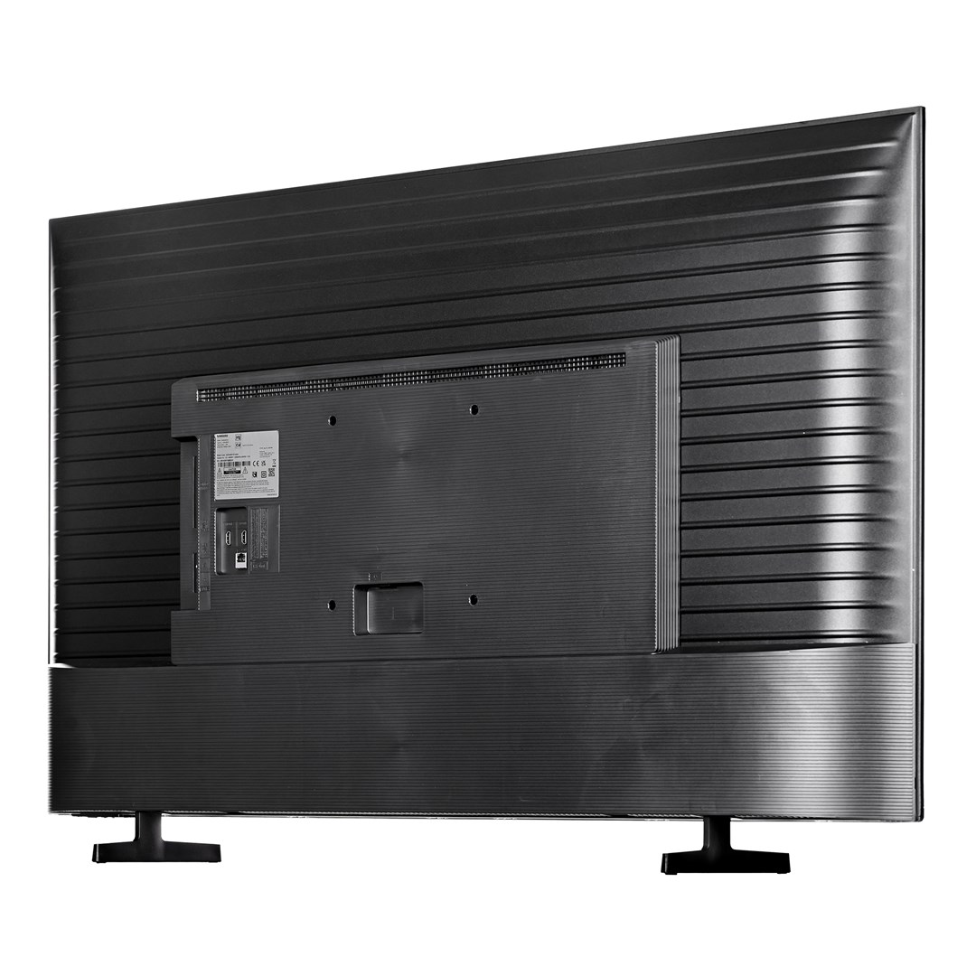 Parte trasera de un televisor negro. Muestra el panel trasero con varios puertos, un panel central y dos patas negras que sostienen el televisor.