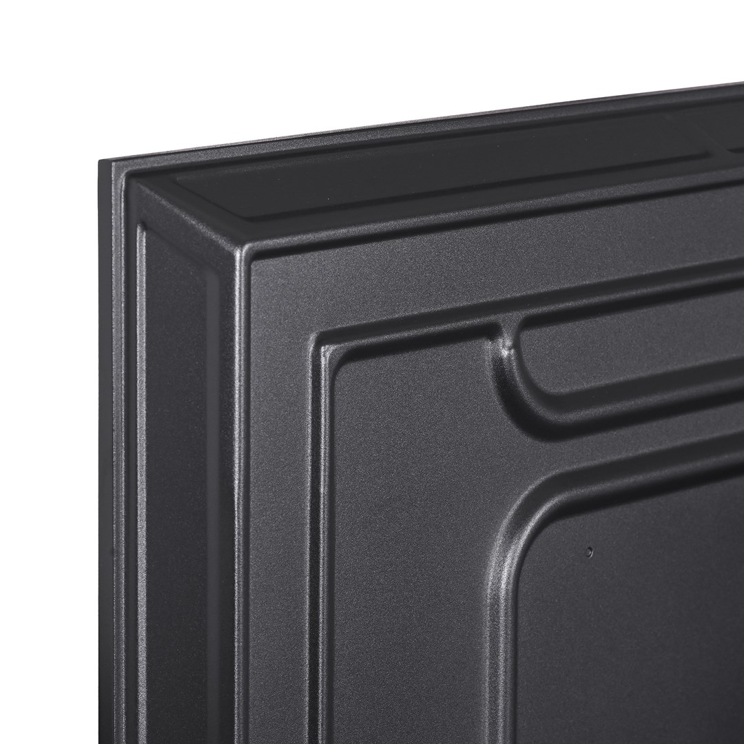 Zbliżenie ciemnoszarego, teksturowanego panelu z wypukłymi prostokątnymi i zakrzywionymi wzorami. Panel ma obramowaną krawędź.