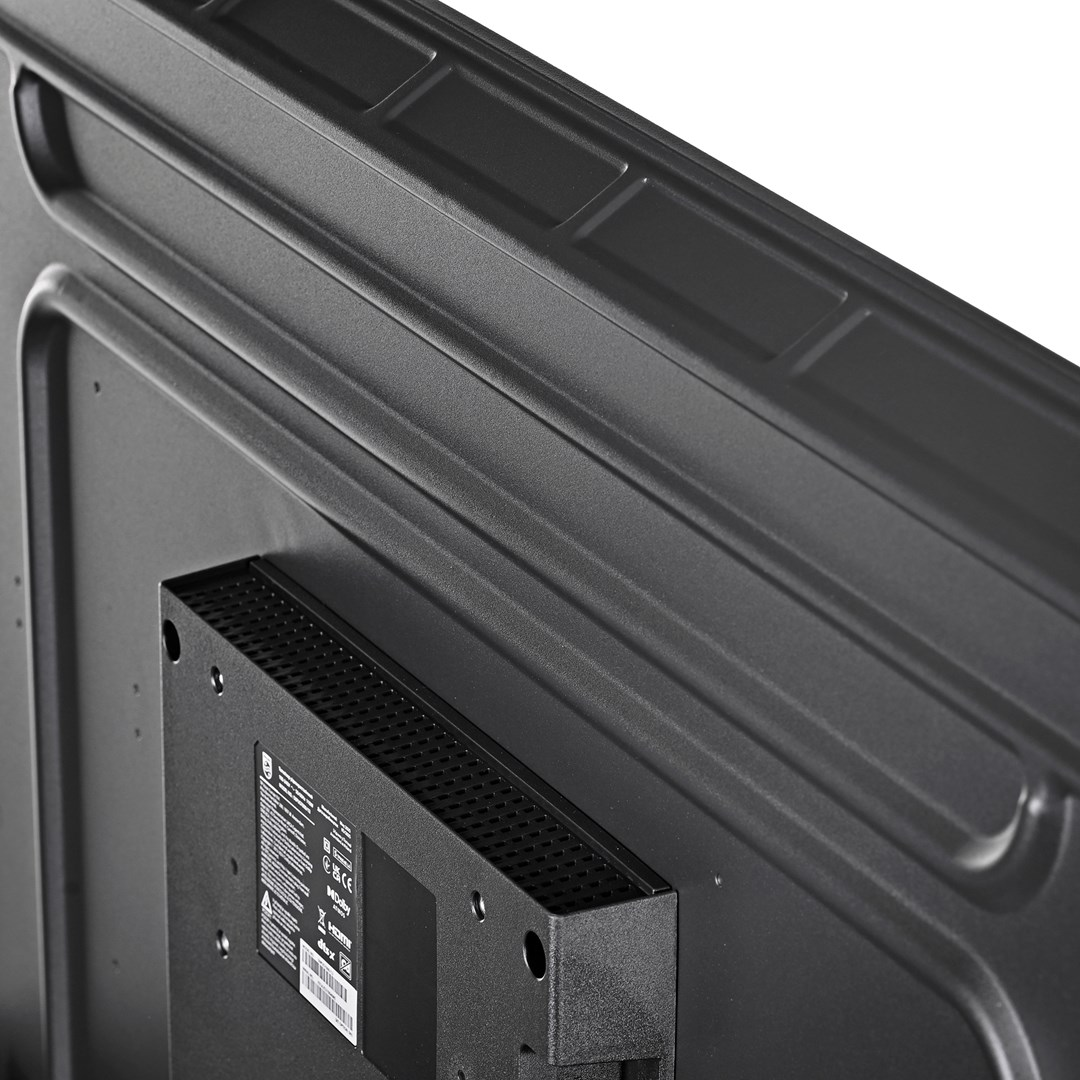 Zbliżenie na tył czarnego telewizora. Widoczna jest zamontowana czarna skrzynka z otworami wentylacyjnymi oraz teksturowana powierzchnia telewizora.