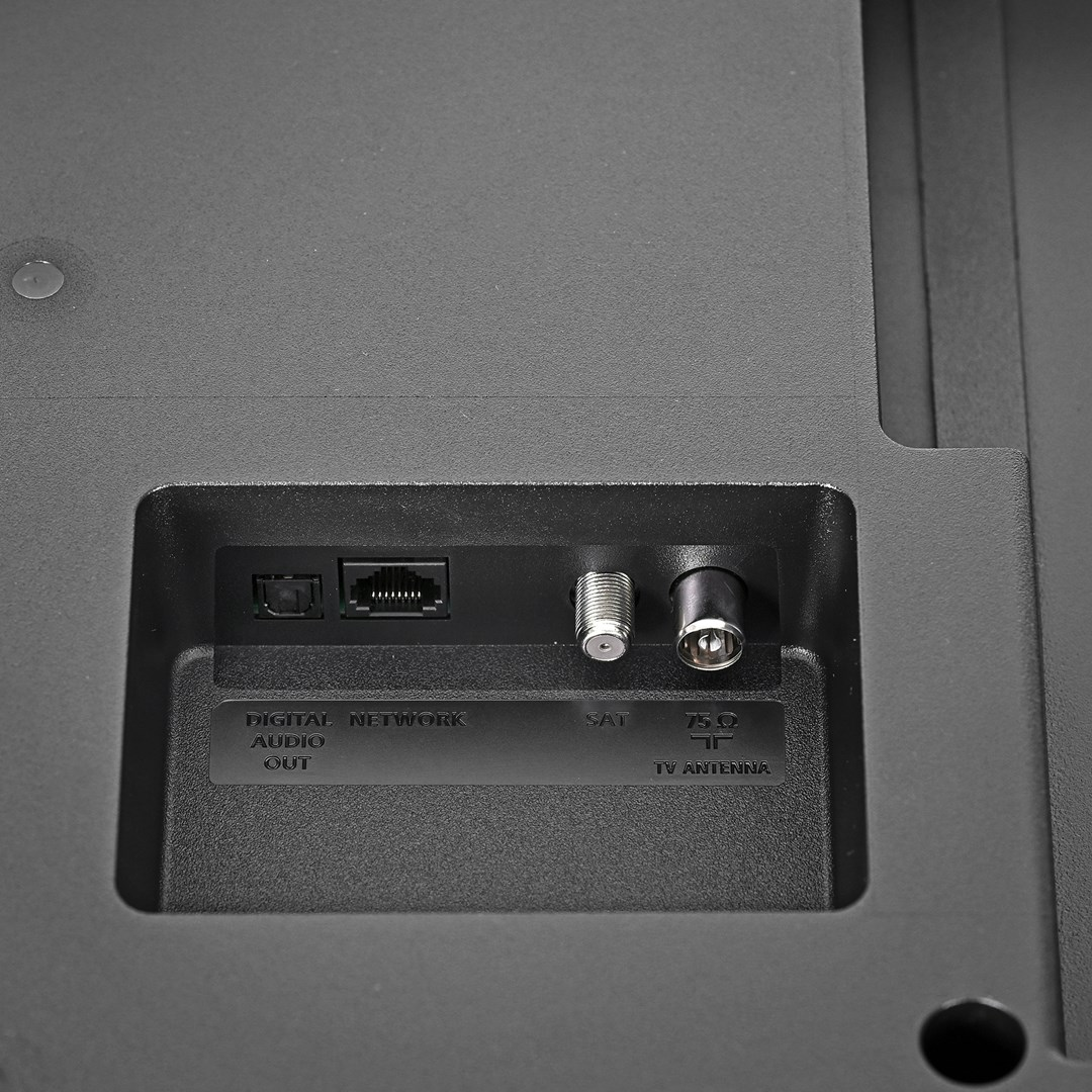 Zbliżenie tylnego panelu telewizora z różnymi portami wejściowymi: sieć cyfrowa, wyjście audio, SAT i antena TV. Ciemnoszary plastik.
