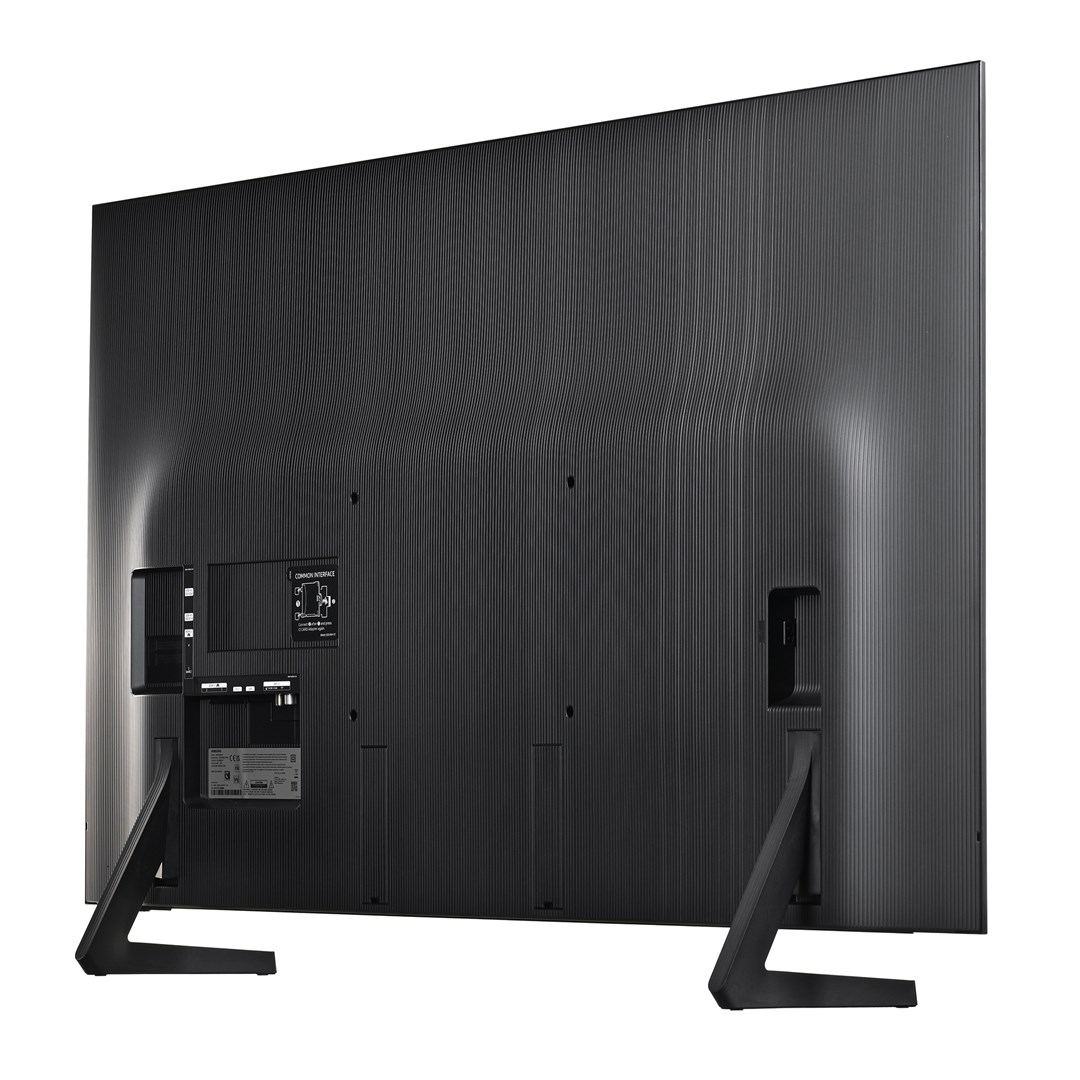 Vista posteriore di un grande televisore Samsung nero. Ha un retro strutturato con porte e un supporto. Le gambe sono nere.