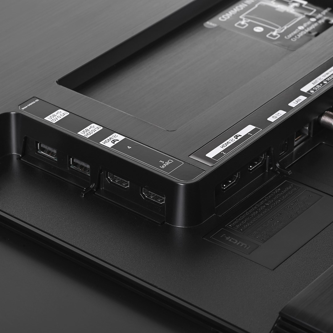 Gros plan sur le panneau arrière d'un téléviseur avec divers ports : HDMI, USB, LAN et autres. Le panneau est noir avec des étiquettes blanches.