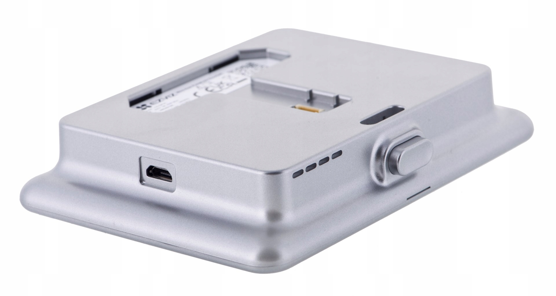 Srebrne urządzenie elektroniczne z zakrzywioną podstawą, przyciskiem i małym portem. Góra ma szczeliny i złącze.