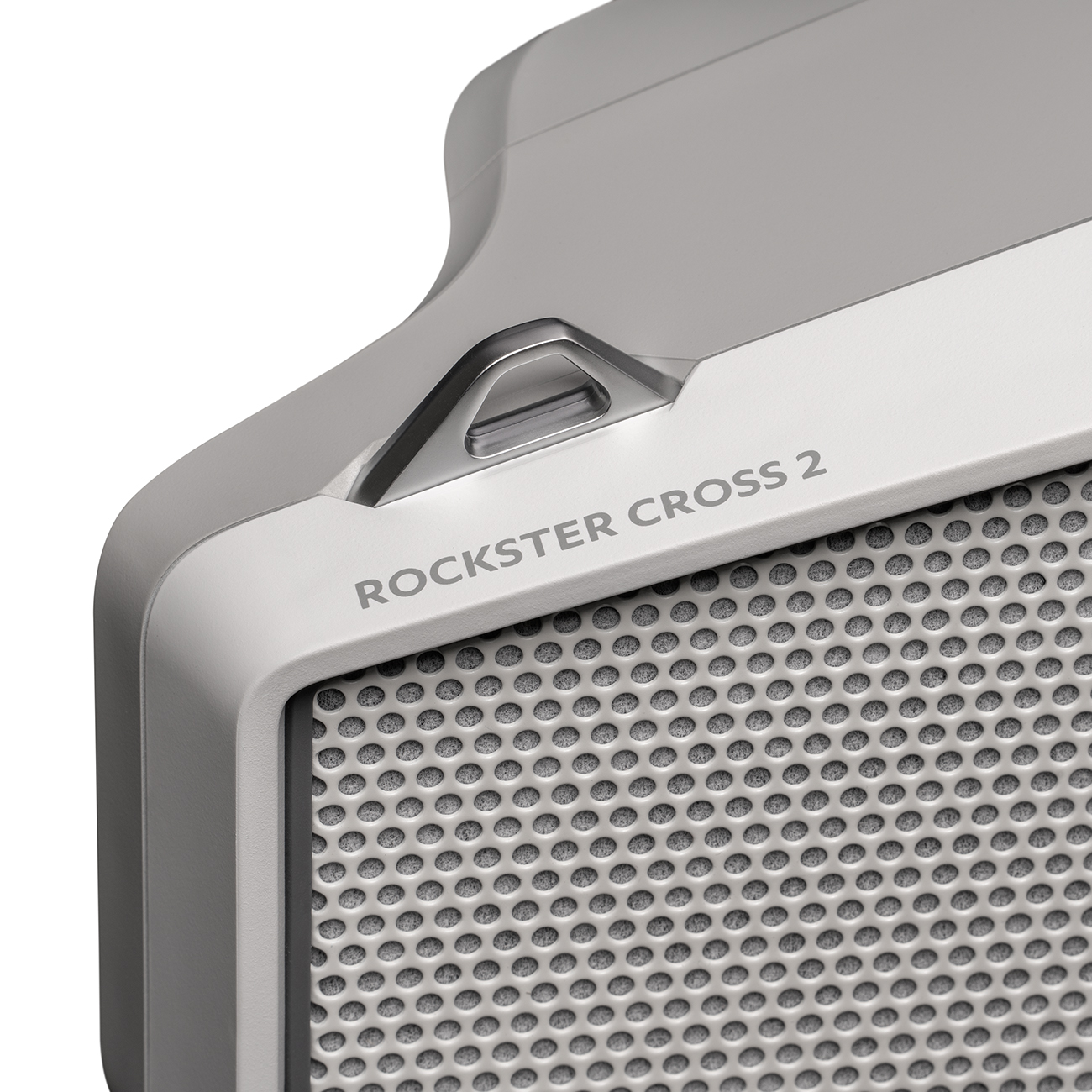 Close-up van een lichtgrijze luidspreker. Het heeft een metalen rooster, een handvat en de tekst 'ROCKSTER CROSS 2'.