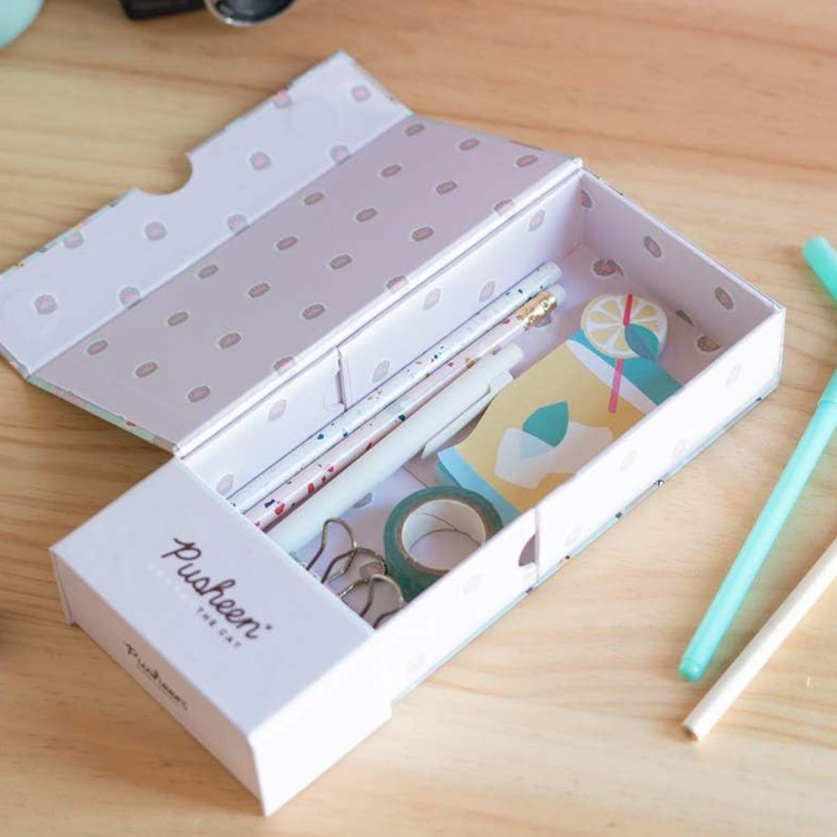 Geöffnete Federtasche mit Stiften, Washi-Tape und einer Zitronengetränkekarte auf Holzoberfläche.