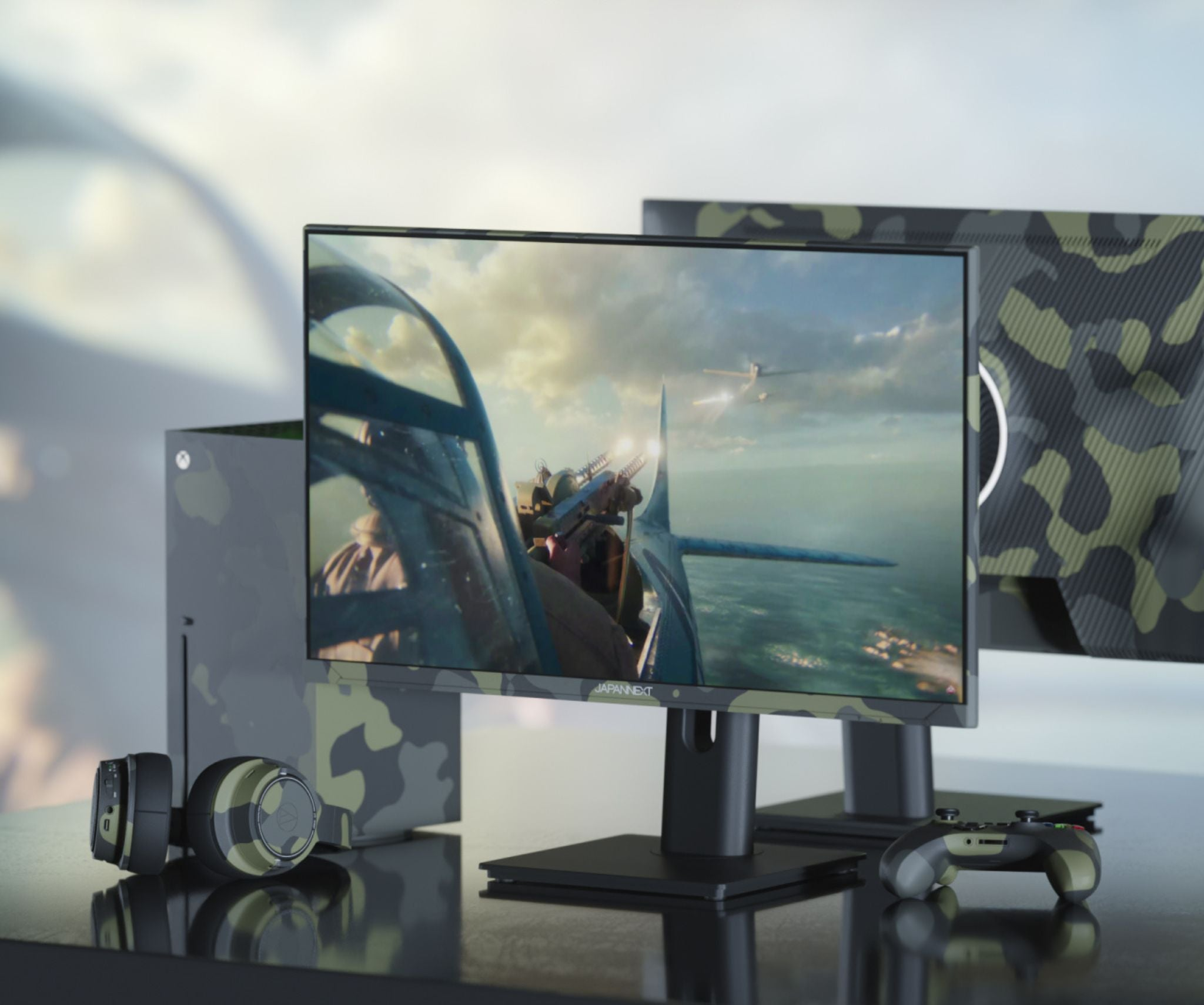 A gaming setup with a monitor displaying a plane in combat.  Headphones, console, and controller are also visible.