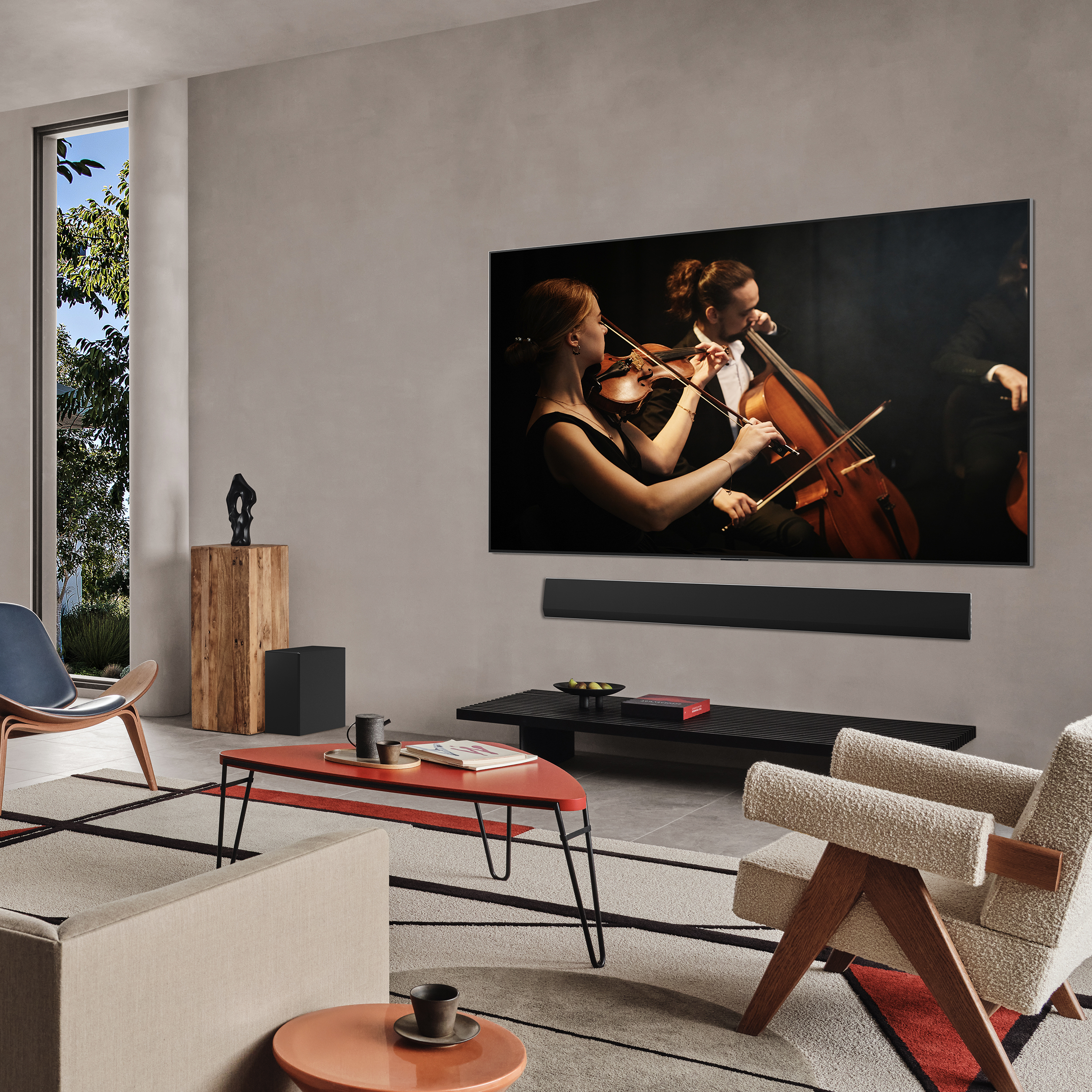 Un salon moderne avec une grande télévision montrant des musiciens, deux chaises, une table basse et une fenêtre.