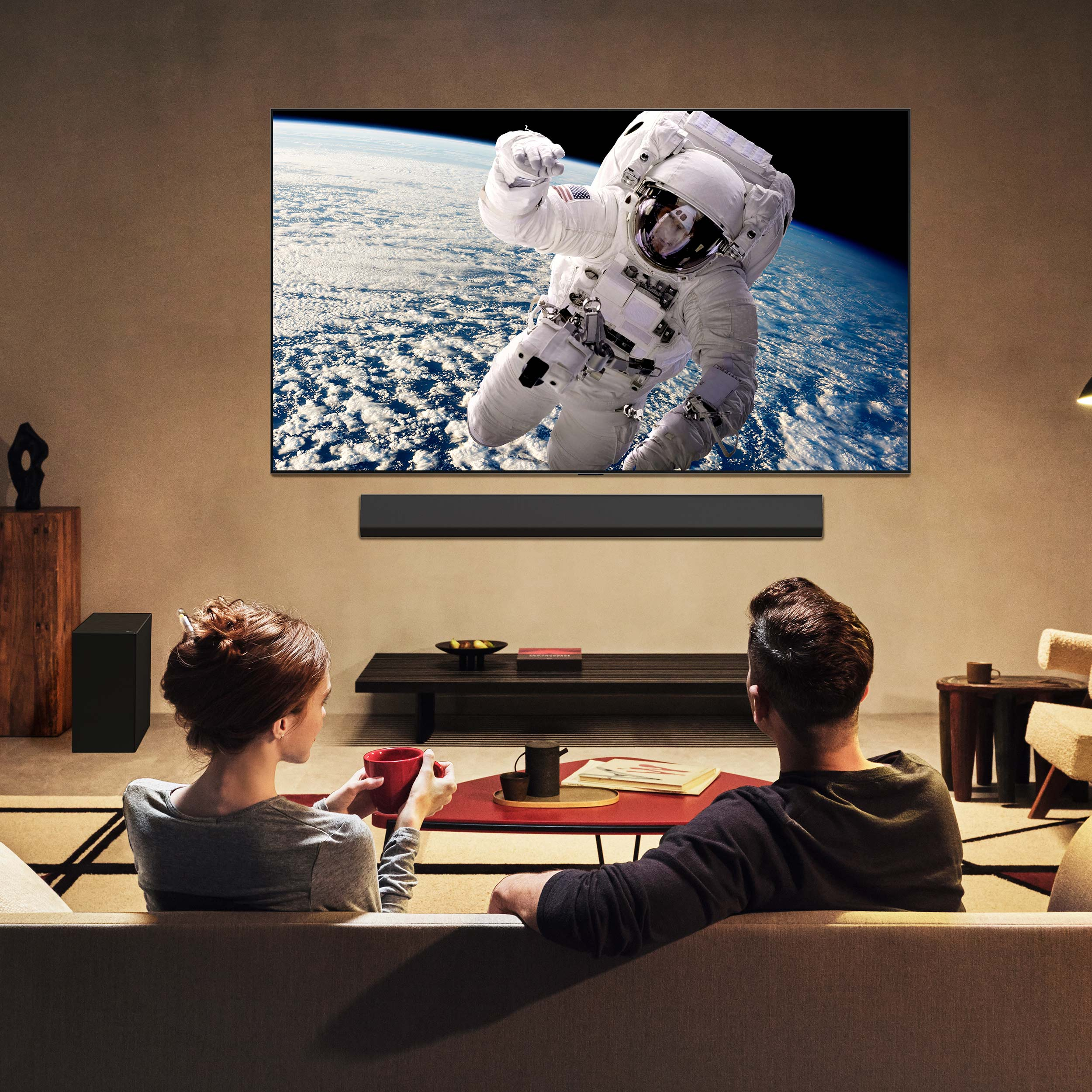Una coppia guarda la TV con un astronauta nello spazio. Sono seduti su un divano con un tavolino.