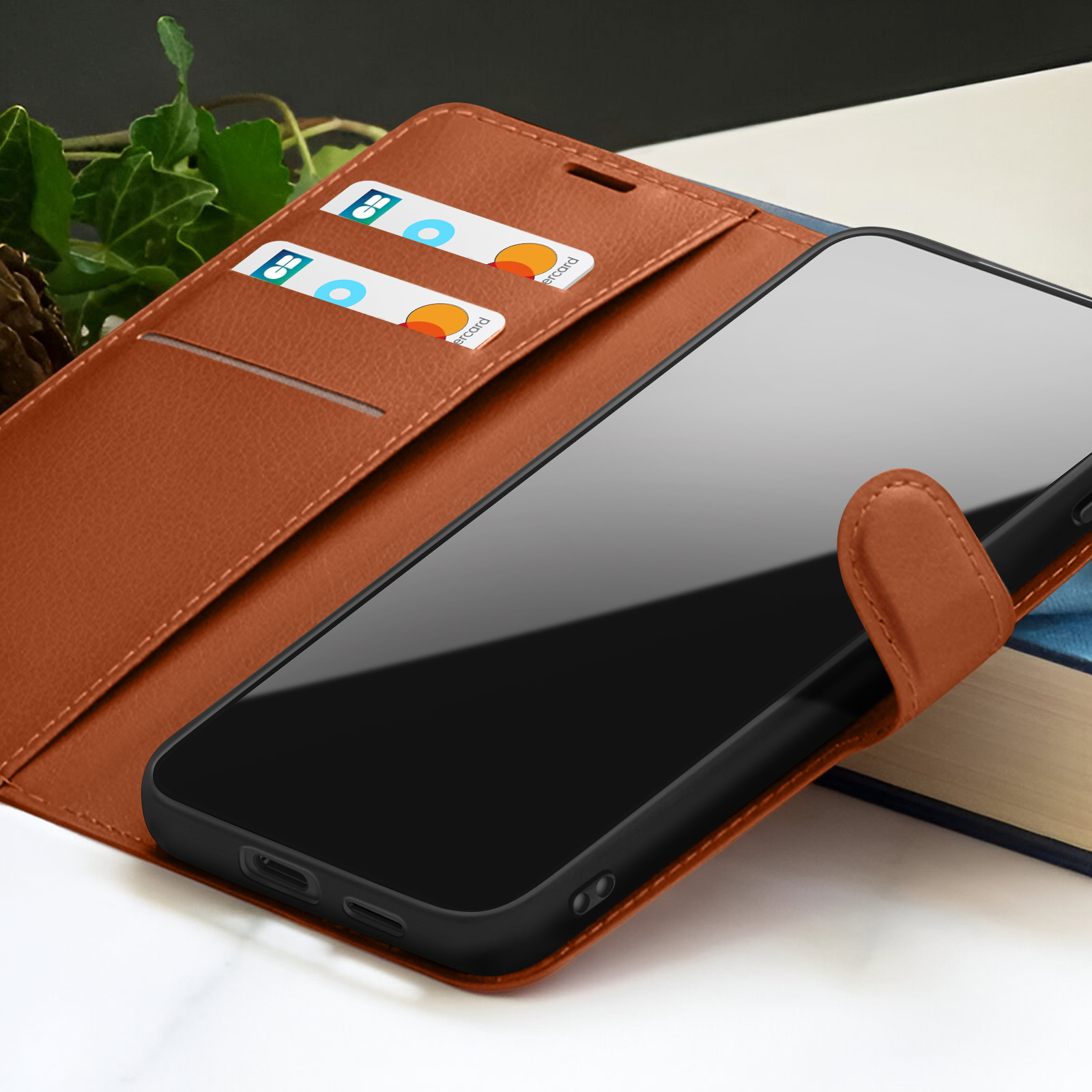 Un étui de téléphone en cuir marron avec un téléphone noir. Des cartes de crédit sont dans l'étui.