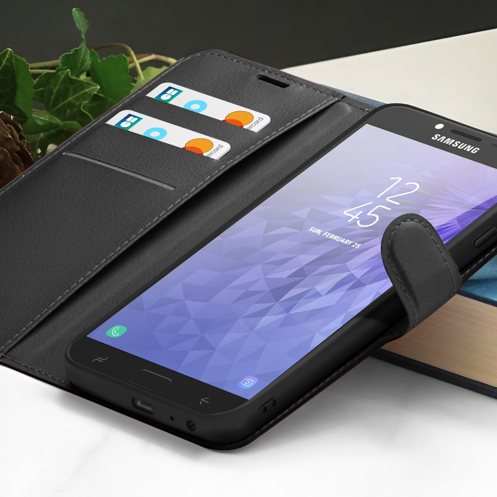 Un téléphone noir dans un étui, affichant l'heure et la date. Deux cartes sont dans l'étui. Le téléphone est sur un livre.