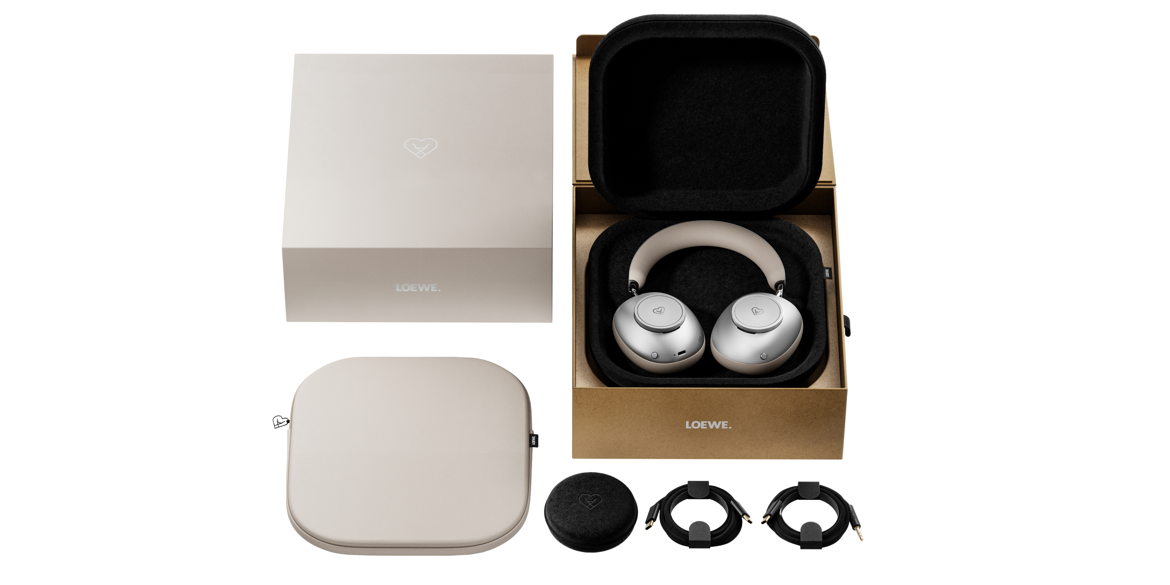 Eine offene Box mit Kopfhörern, einer Hülle und Zubehör. Kopfhörer sind hellgrau und beige. Die Verpackung ist beige und braun.