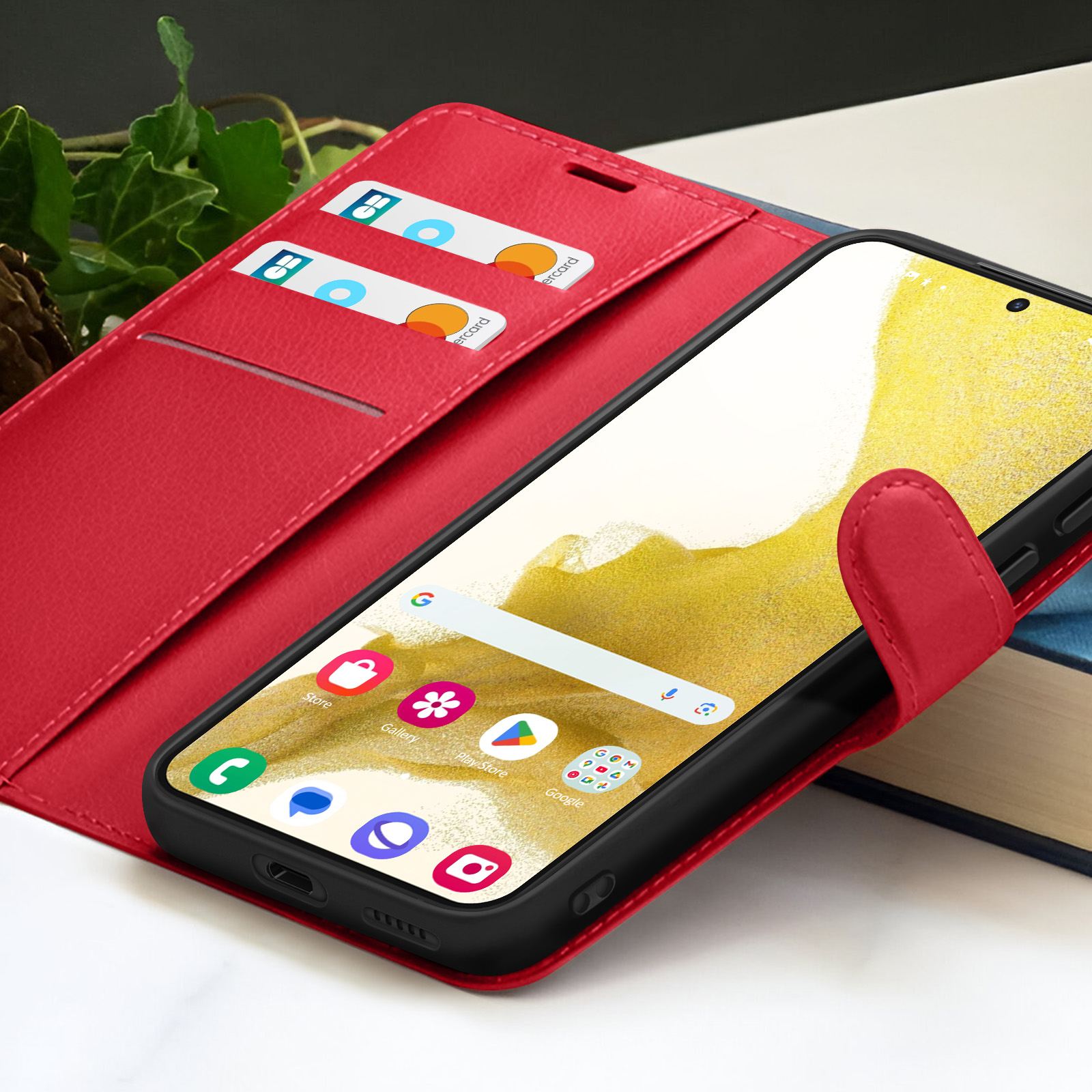 Étui de téléphone rouge avec un téléphone à l'intérieur affichant l'écran d'accueil. Cartes dans la poche gauche. L'étui est ouvert.