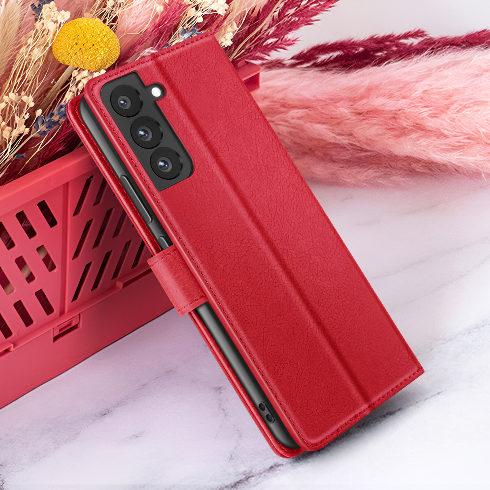 Étui de téléphone rouge sur marbre. Fleurs et un panier rouge en arrière-plan.