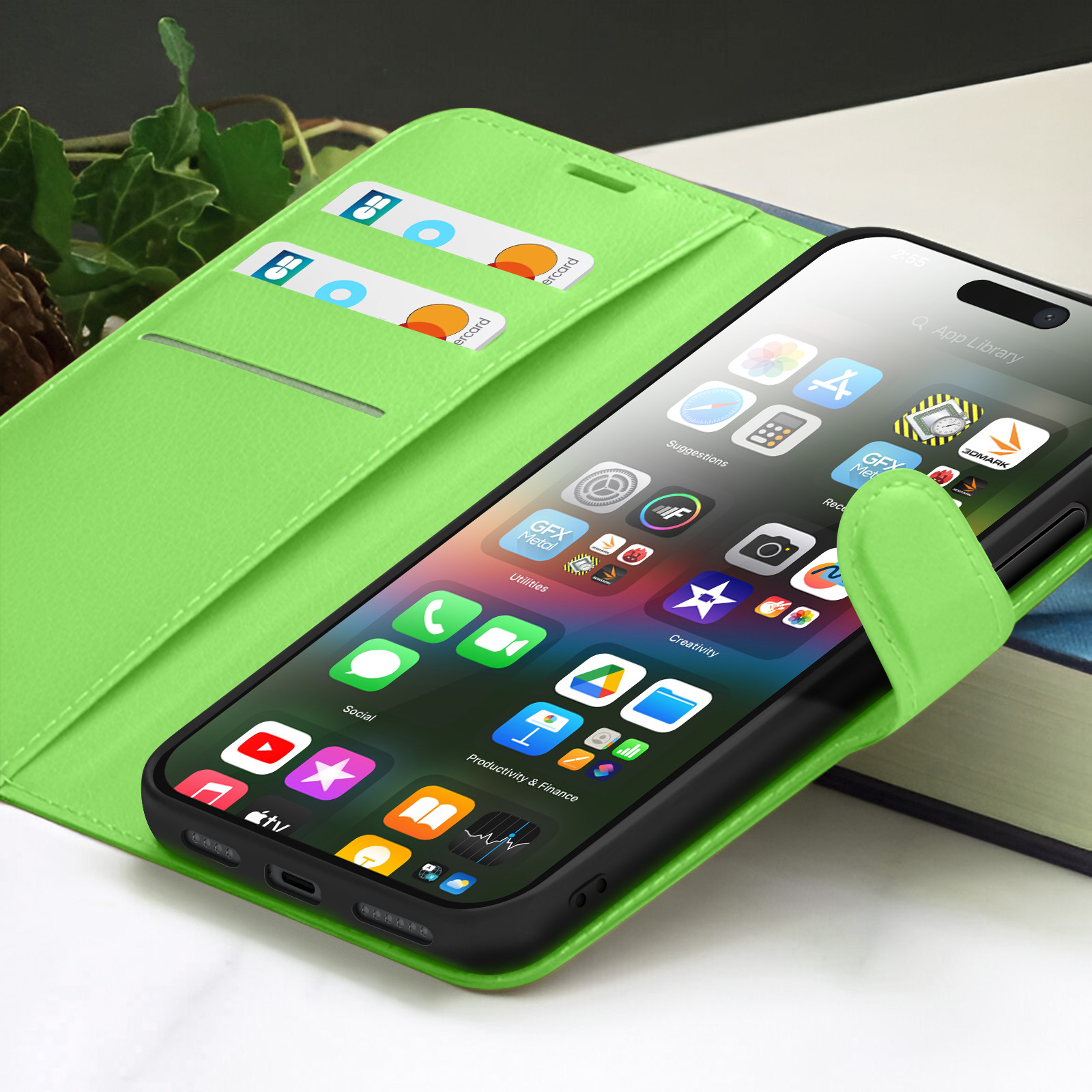 Een iPhone in een groene portemonnee, met app-iconen. Creditcards zichtbaar in de portemonnee. Een boek op de achtergrond.
