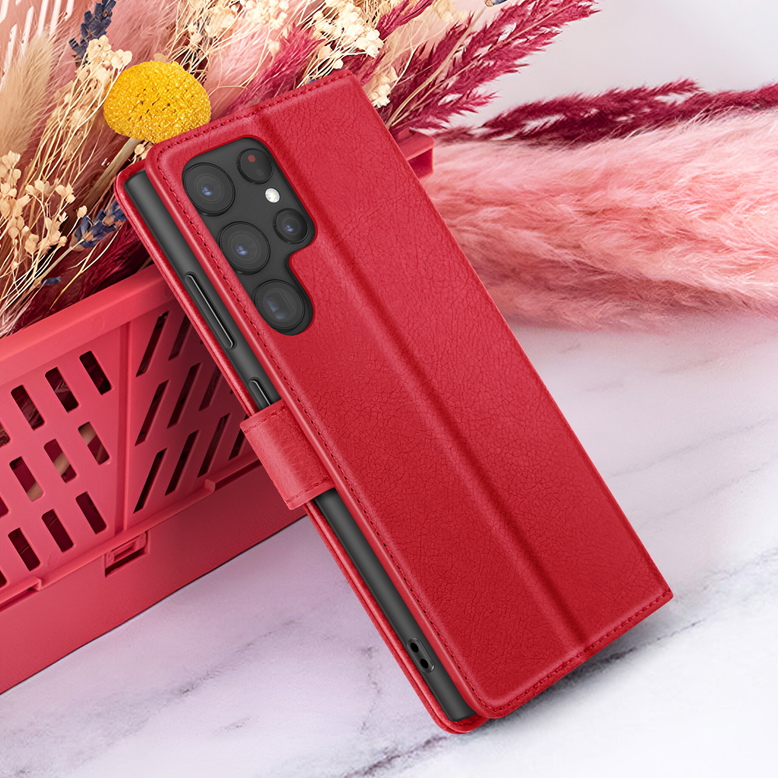 Étui de téléphone rouge avec téléphone sur une caisse rouge, avec des fleurs séchées. Fond en marbre.