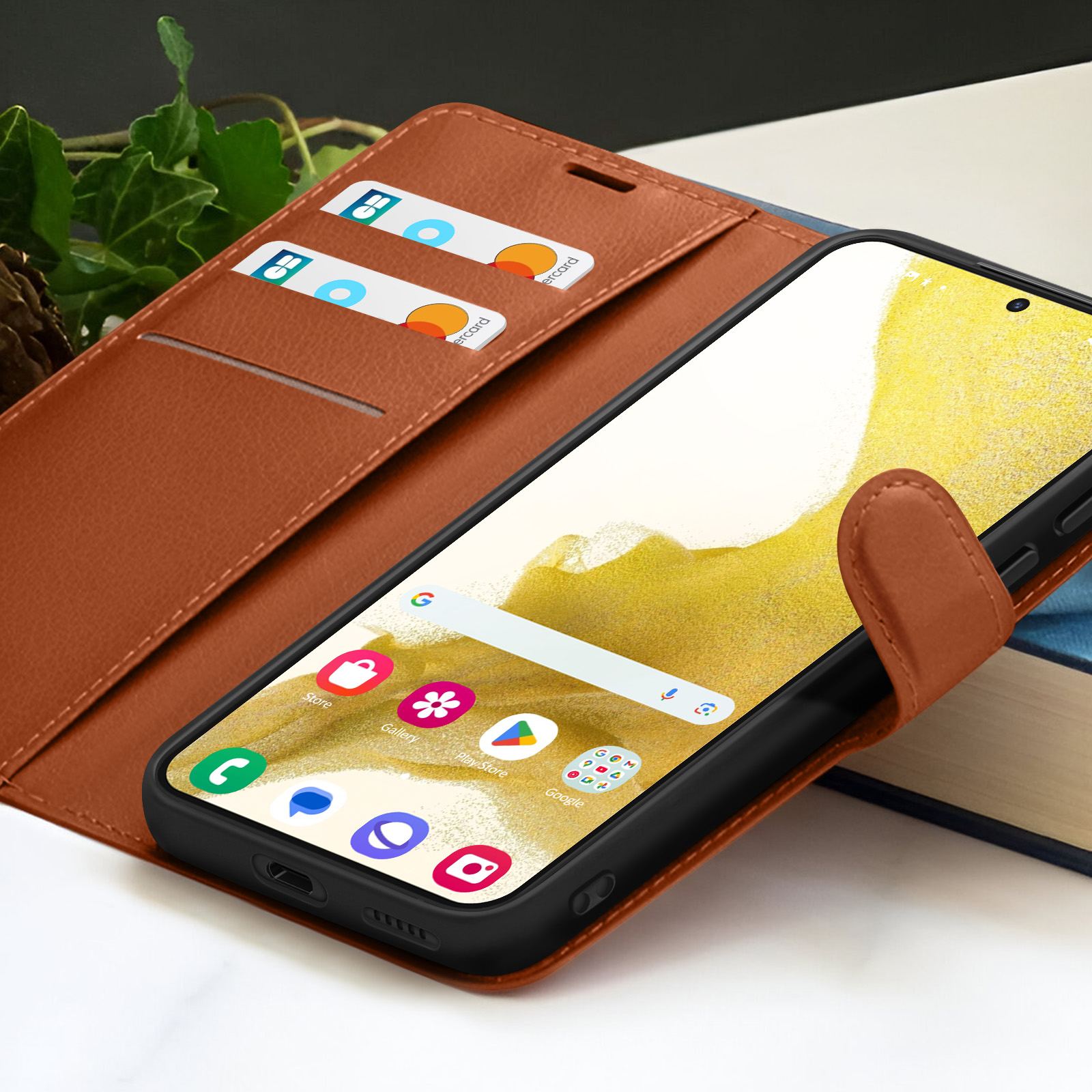Un téléphone dans un étui en cuir marron. Des cartes de crédit sont dans l'étui. L'écran affiche des applications.