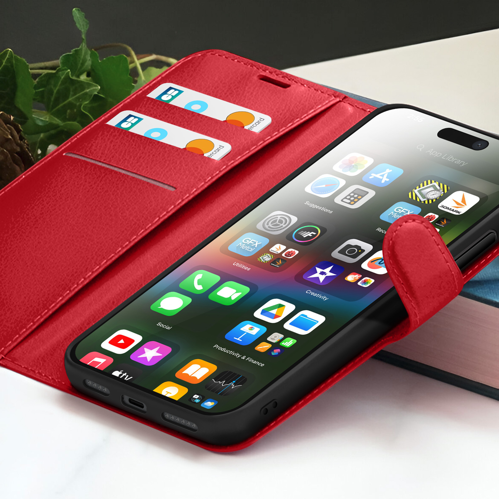 Een smartphone met apps zit in een rode hoes. Twee creditcards zitten in een sleuf. Boeken op de achtergrond.