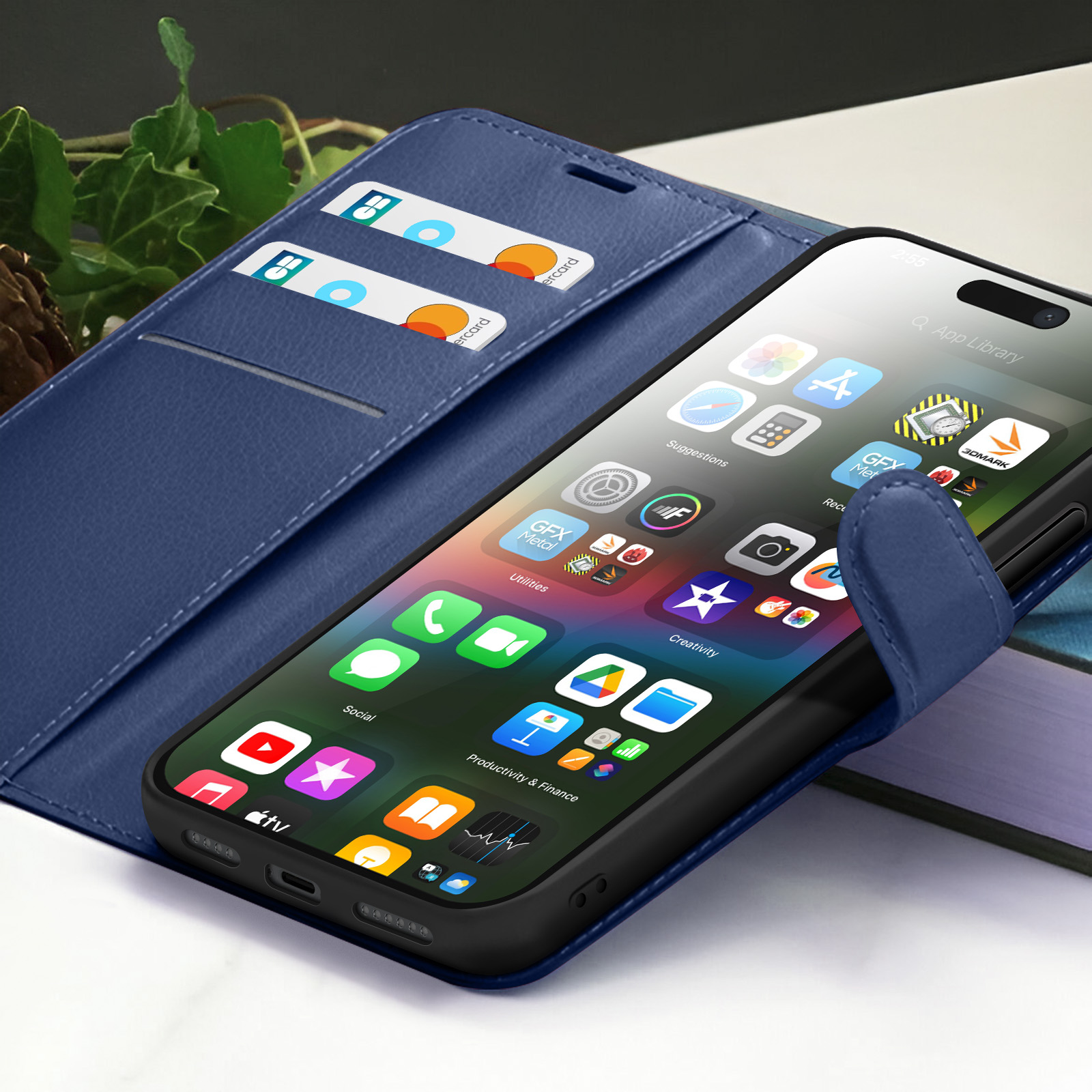 Een smartphone met apps zit in een blauwe hoes met kaarten, op een tafel. Groene bladeren op de achtergrond.