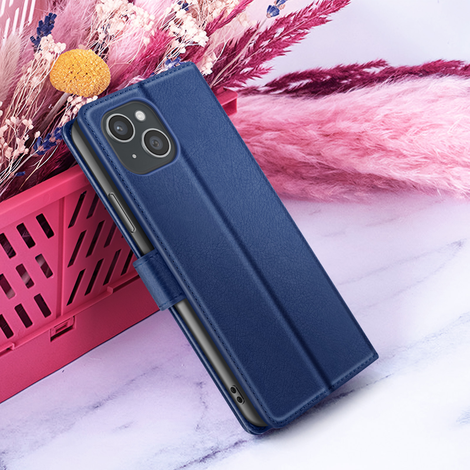 Een blauwe telefoonhoes met een telefoon erin. Roze bloemen en een roze mand op de achtergrond.