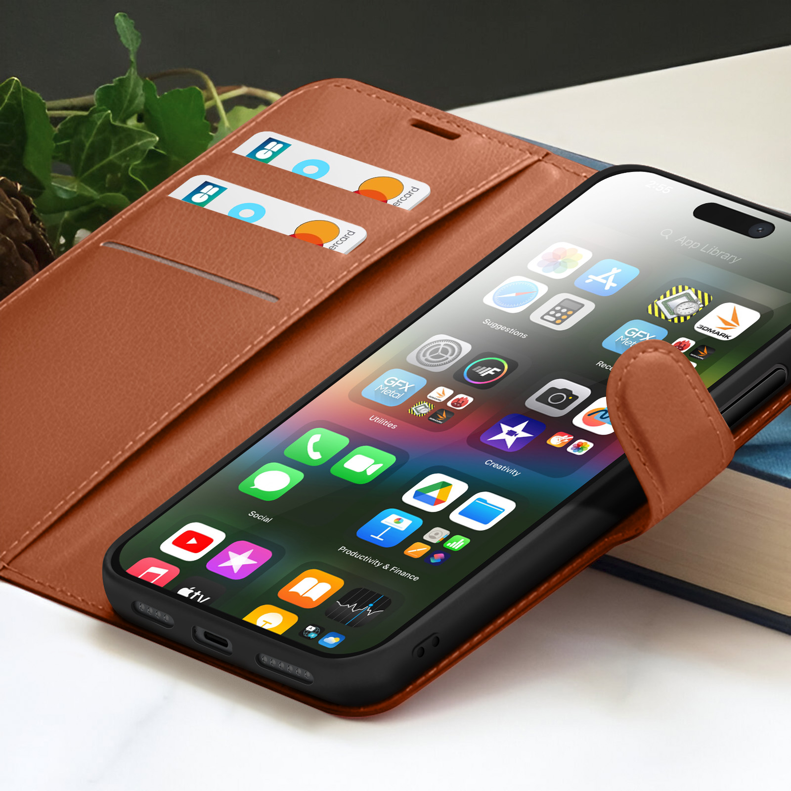Een smartphone met apps zit in een bruine leren hoes. Creditcards zitten in de hoes. Boeken op de achtergrond.