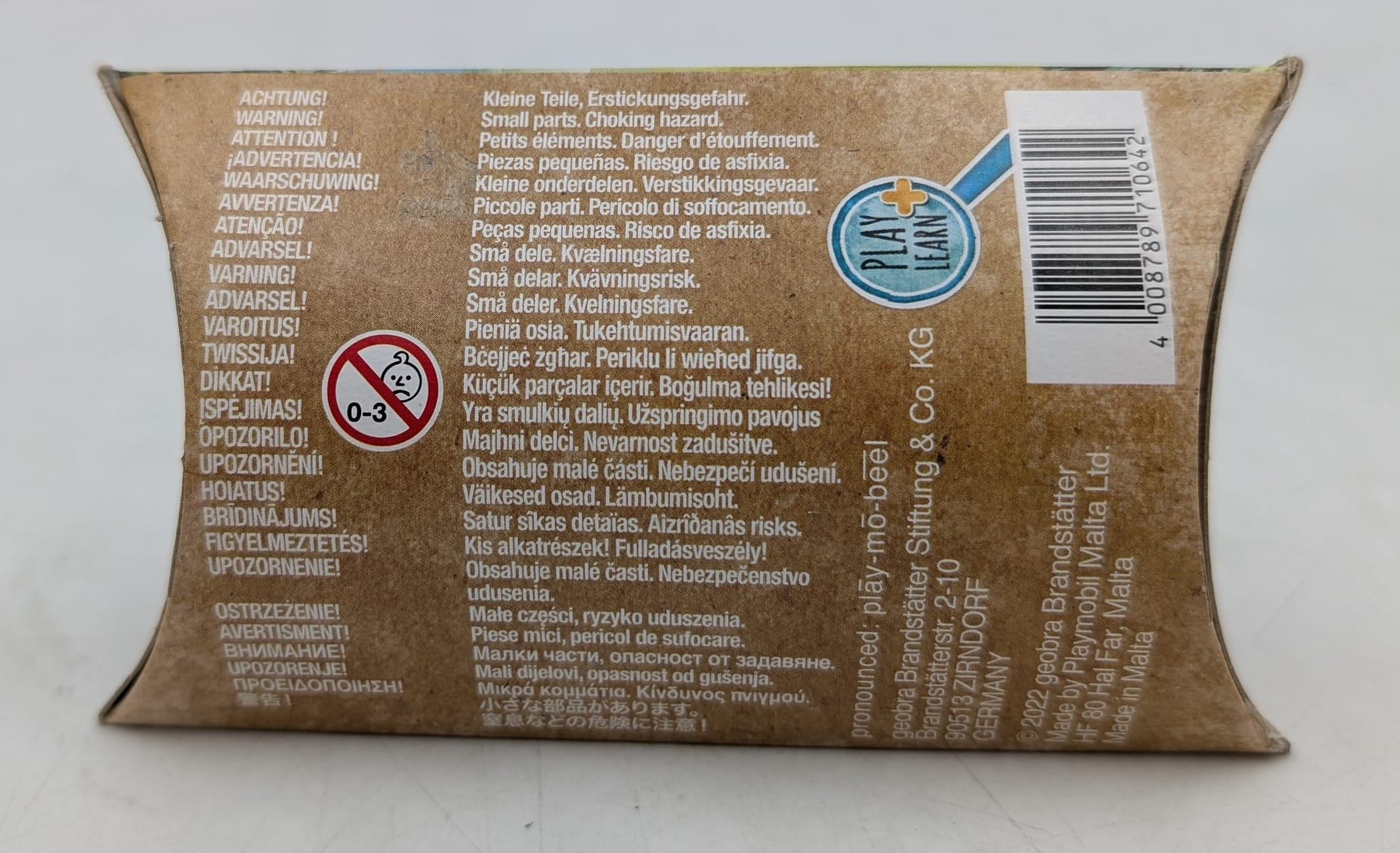 Pudełko z ostrzeżeniami w wielu językach, w tym 'ryzyko zadławienia'. Posiada ostrzeżenie wiekowe '0-3'.