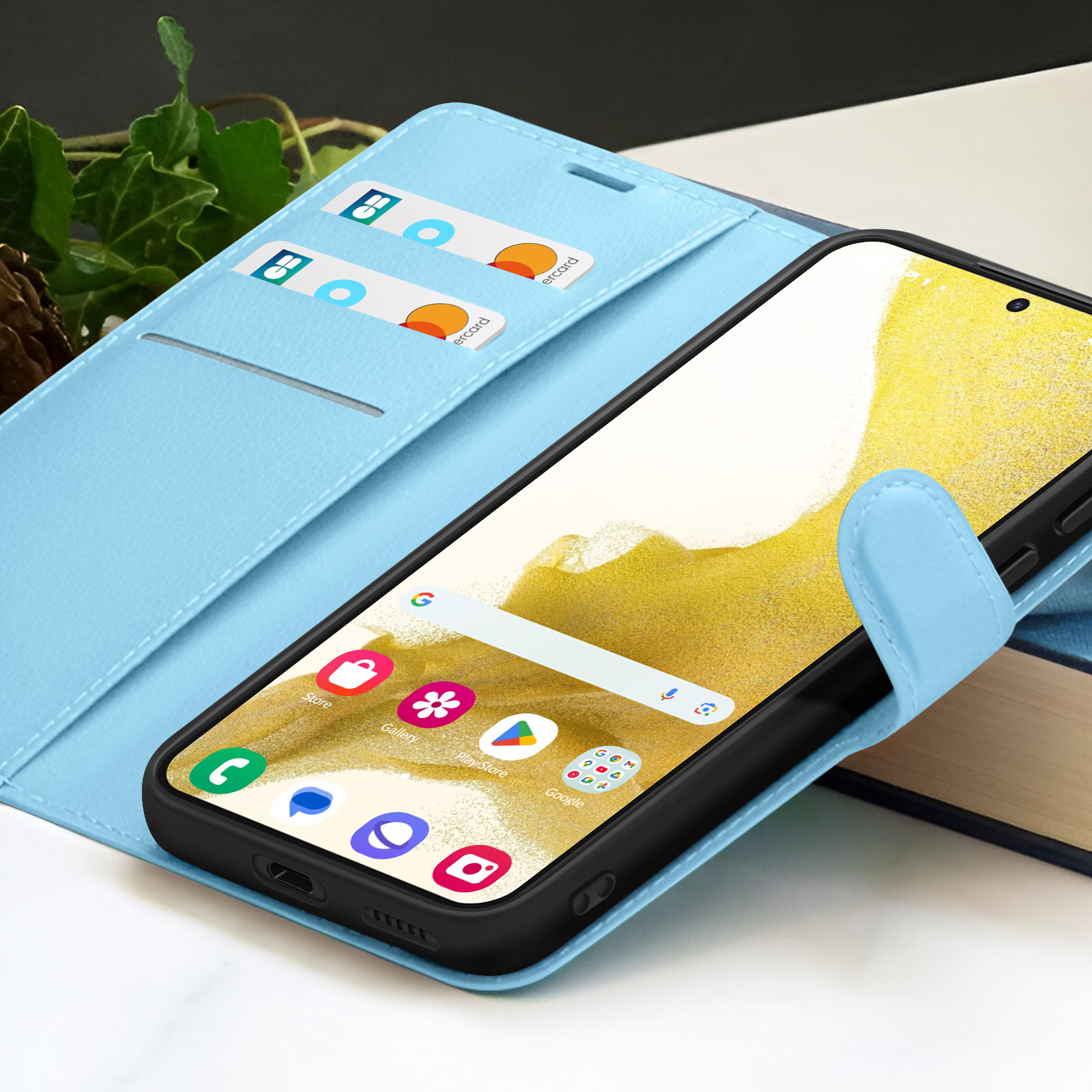 Un smartphone dans un étui bleu clair, ouvert pour révéler l'écran. Cartes dans l'étui. Livres en arrière-plan.