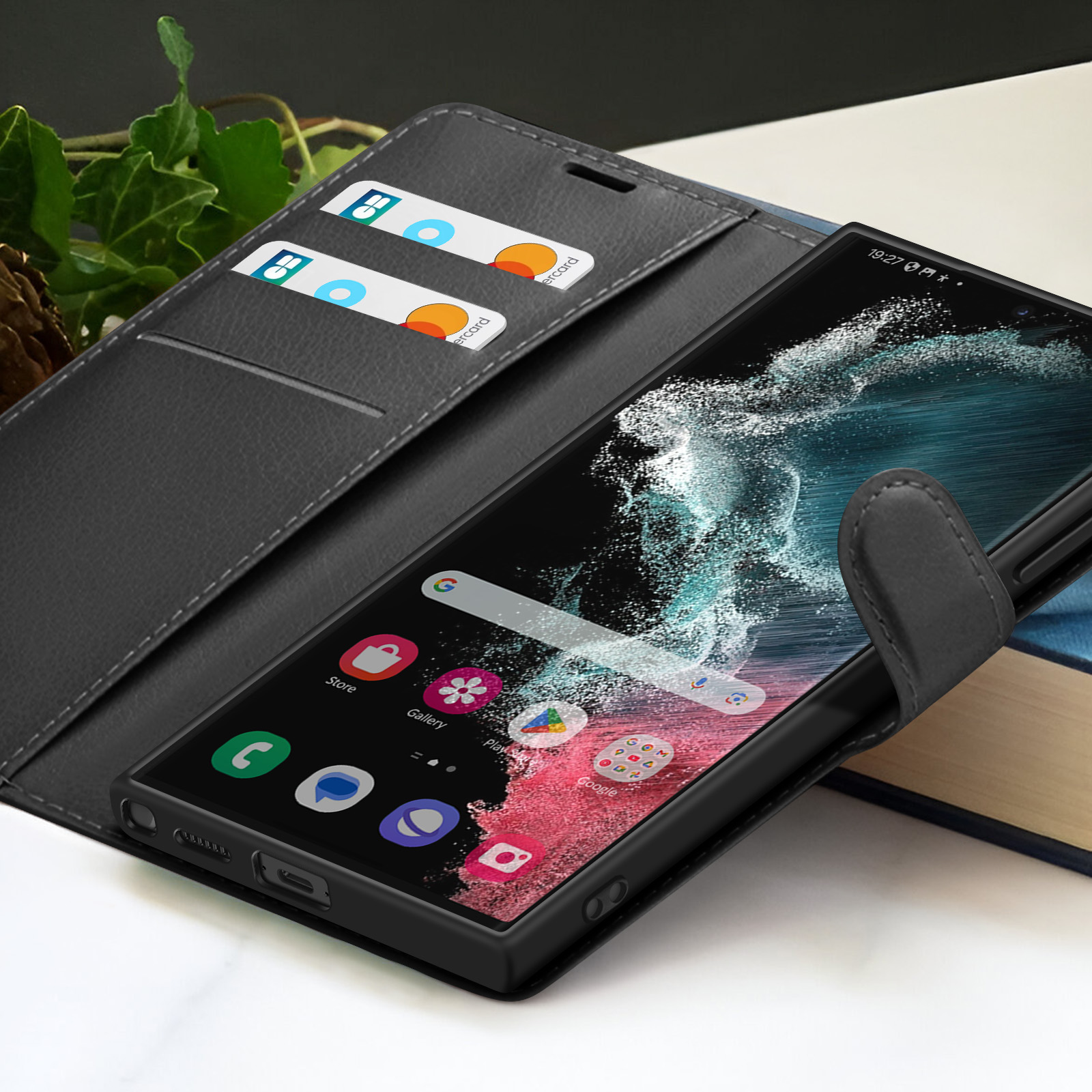 Un smartphone dans un étui en cuir noir avec cartes de crédit à l'intérieur. Affiche applications et heure. Arrière-plan avec livre.