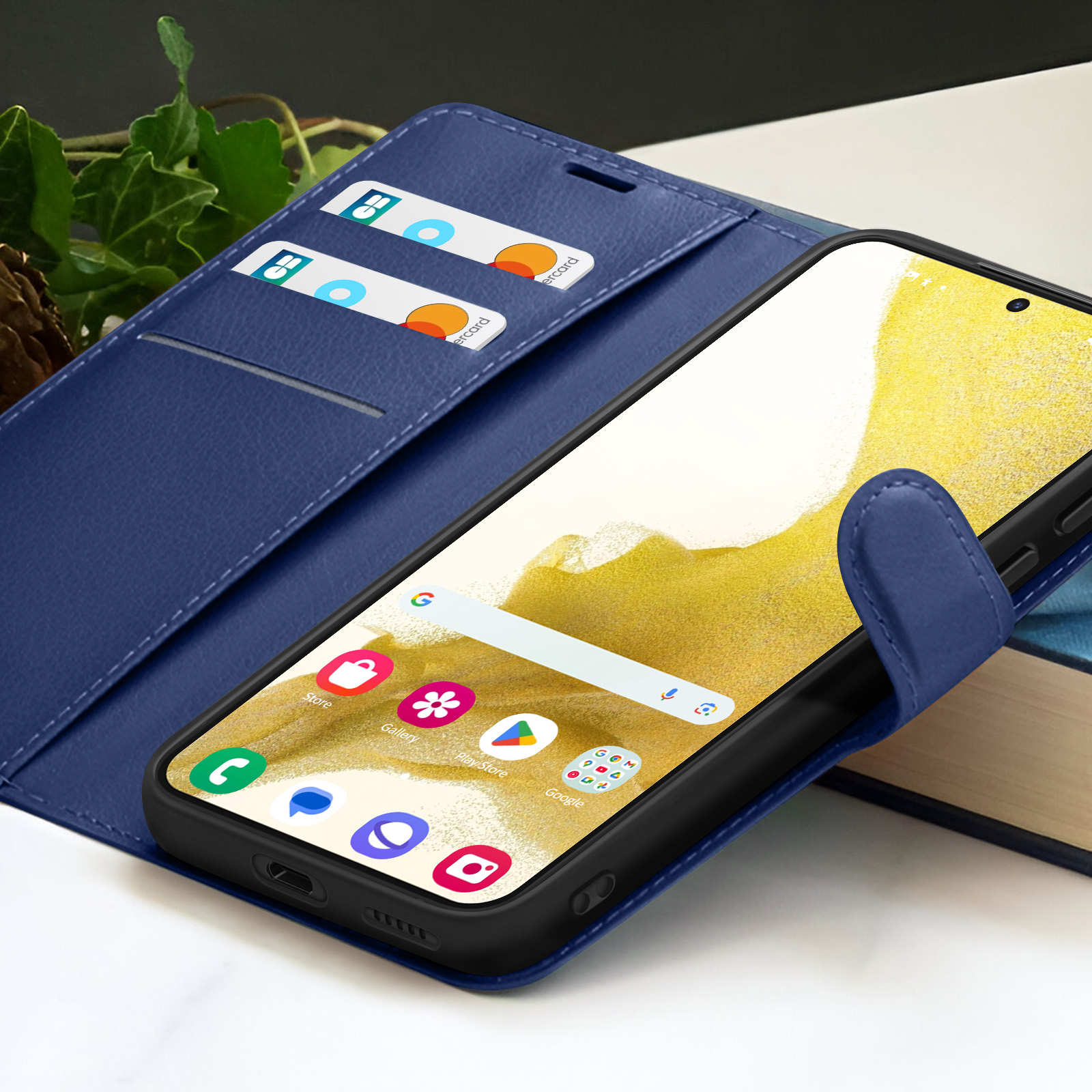Un étui de téléphone bleu avec un smartphone, des cartes et un livre. Le téléphone affiche des icônes d'applications.