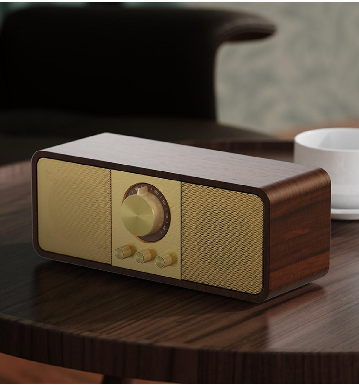 Ein Radio im Vintage-Stil steht auf einem Holztisch, mit goldfarbener Gitterfront, Holzrahmen und goldenen Knöpfen. Im Hintergrund eine Tasse.