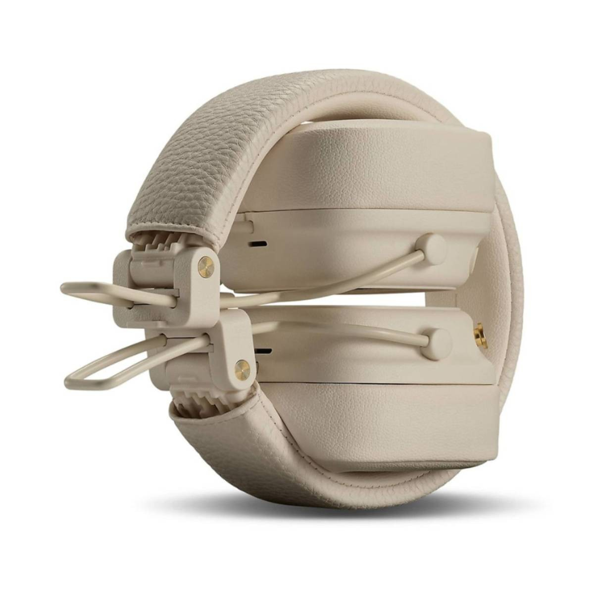 Auriculares plegados de color crema. Los auriculares están apilados, conectados por una diadema y bisagras color crema, sobre un fondo blanco.