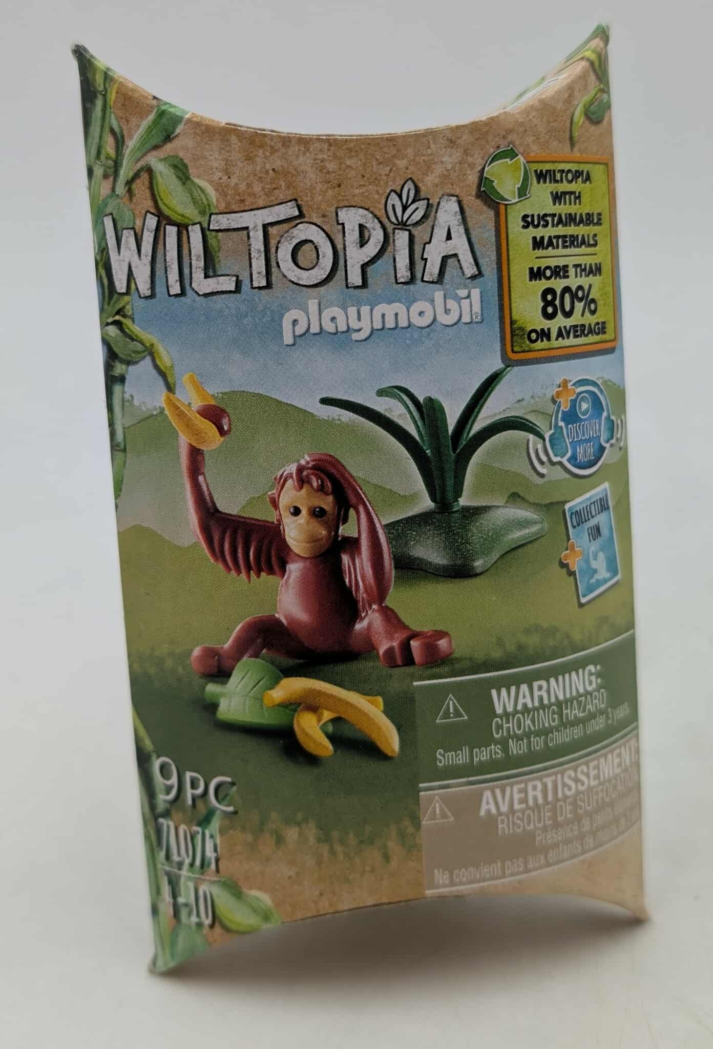 A Playmobil box features a monkey toy with bananas. The box has 'Wiltopia' and 'Playmobil' on it, with sustainability details.