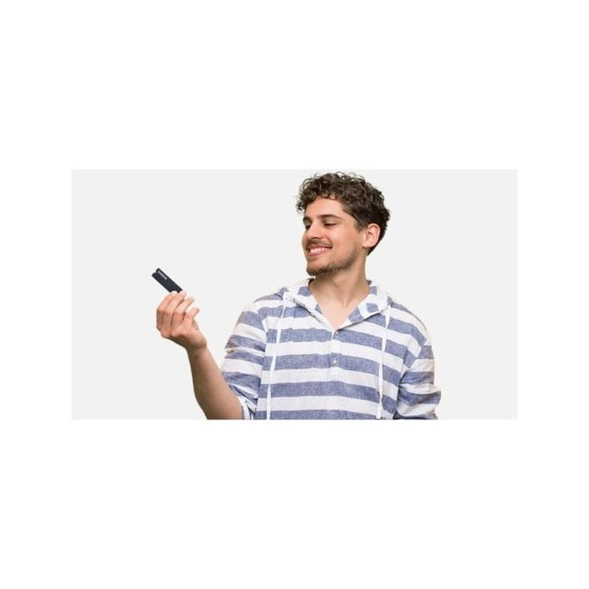 Uśmiechnięty mężczyzna z kręconymi włosami trzyma czarny przedmiot, ubrany w koszulę w paski, na białym tle.