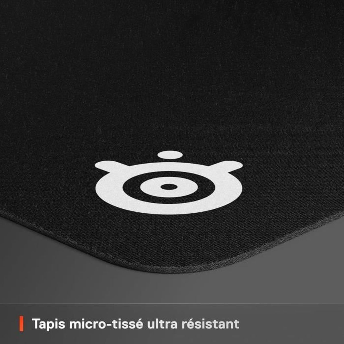 Een zwarte muismat met een wit SteelSeries-logo in de hoek. De textuur is zichtbaar. Onderaan staat: Tapis micro-tissé ultra résistant.
