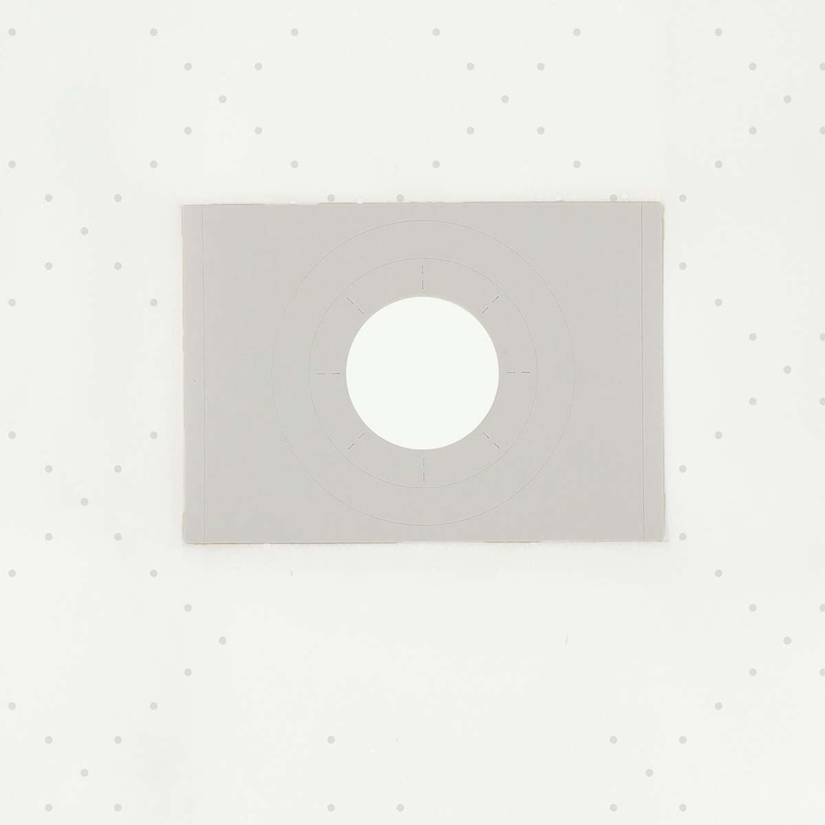 A light gray rectangular card with a central white circle. Dotted background. Circles are marked on the card. 