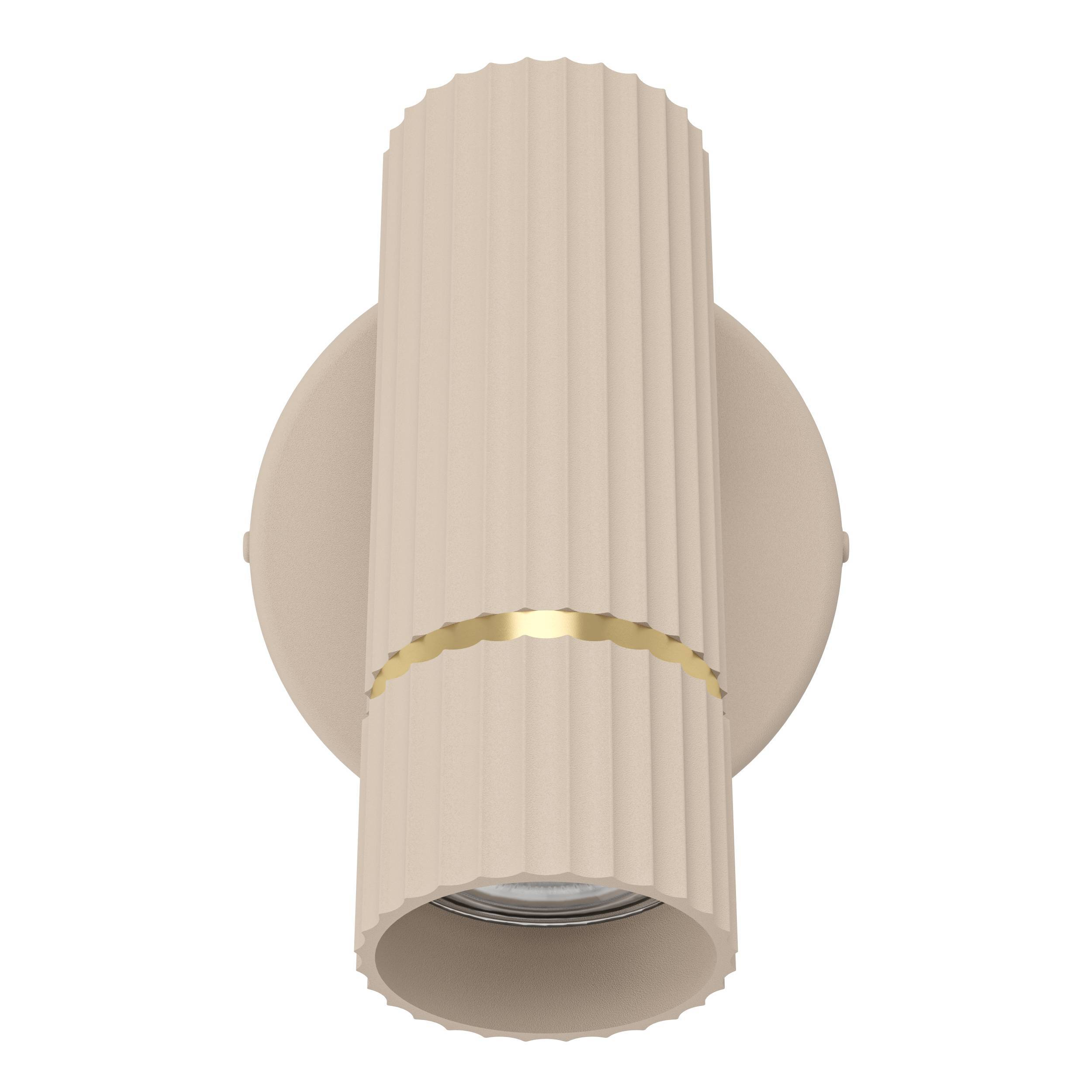 Un apparecchio di illuminazione beige cilindrico con scanalature verticali e un accento dorato, montato su base rotonda.