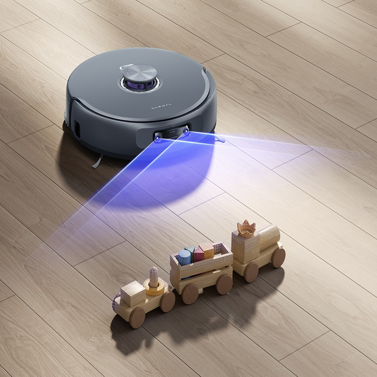 Ein Roboter-Staubsauger und eine Holzspielzeugeisenbahn auf einem Holzboden. Der Staubsauger hat ein blaues Licht.