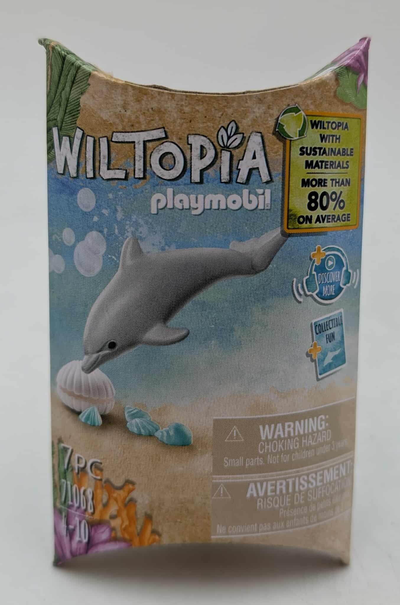 Schachtel mit Delfin-Illustration. Text lautet 'Wiltopia' und 'Playmobil'. Enthält eine Warnung vor Erstickungsgefahr.