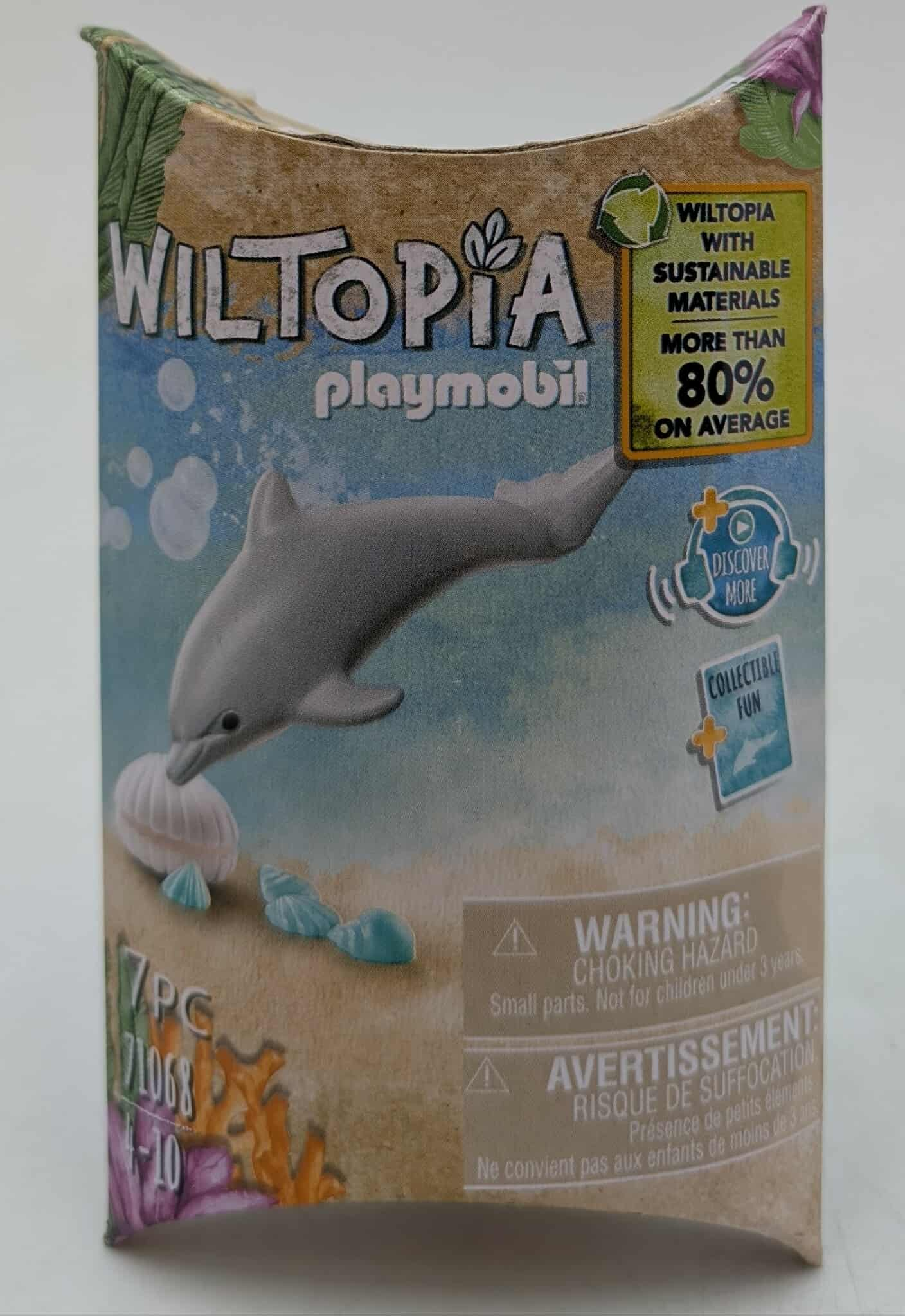 Schachtelkunst für das Wiltopia-Set von Playmobil. Zeigt einen Delfin, eine Muschel und Meereslebewesen. Text enthält Warnungen und nachhaltige Materialien.