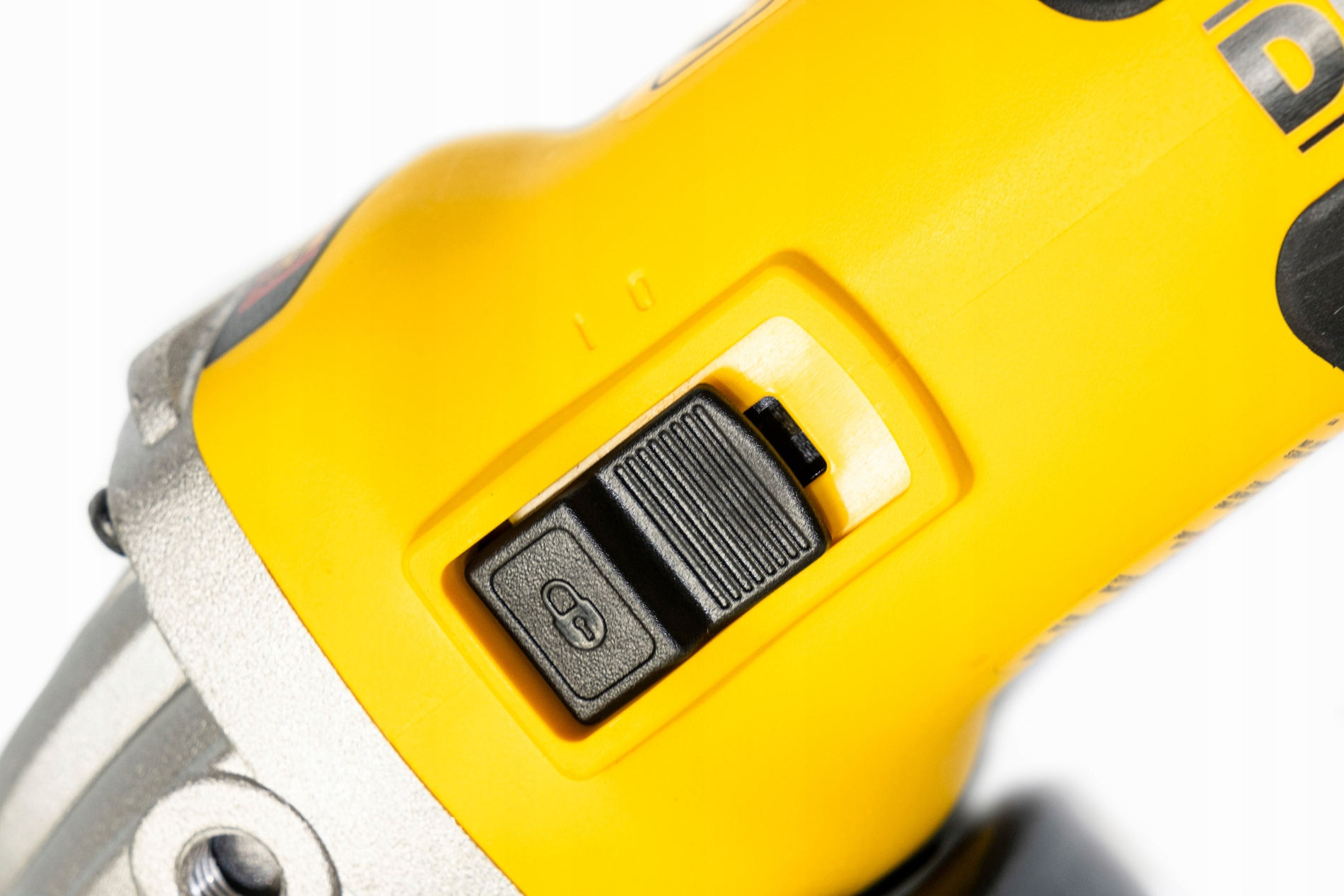 Żółte narzędzie elektryczne z czarnym przełącznikiem w centrum. Przełącznik ma symbol kłódki. Białe tło.