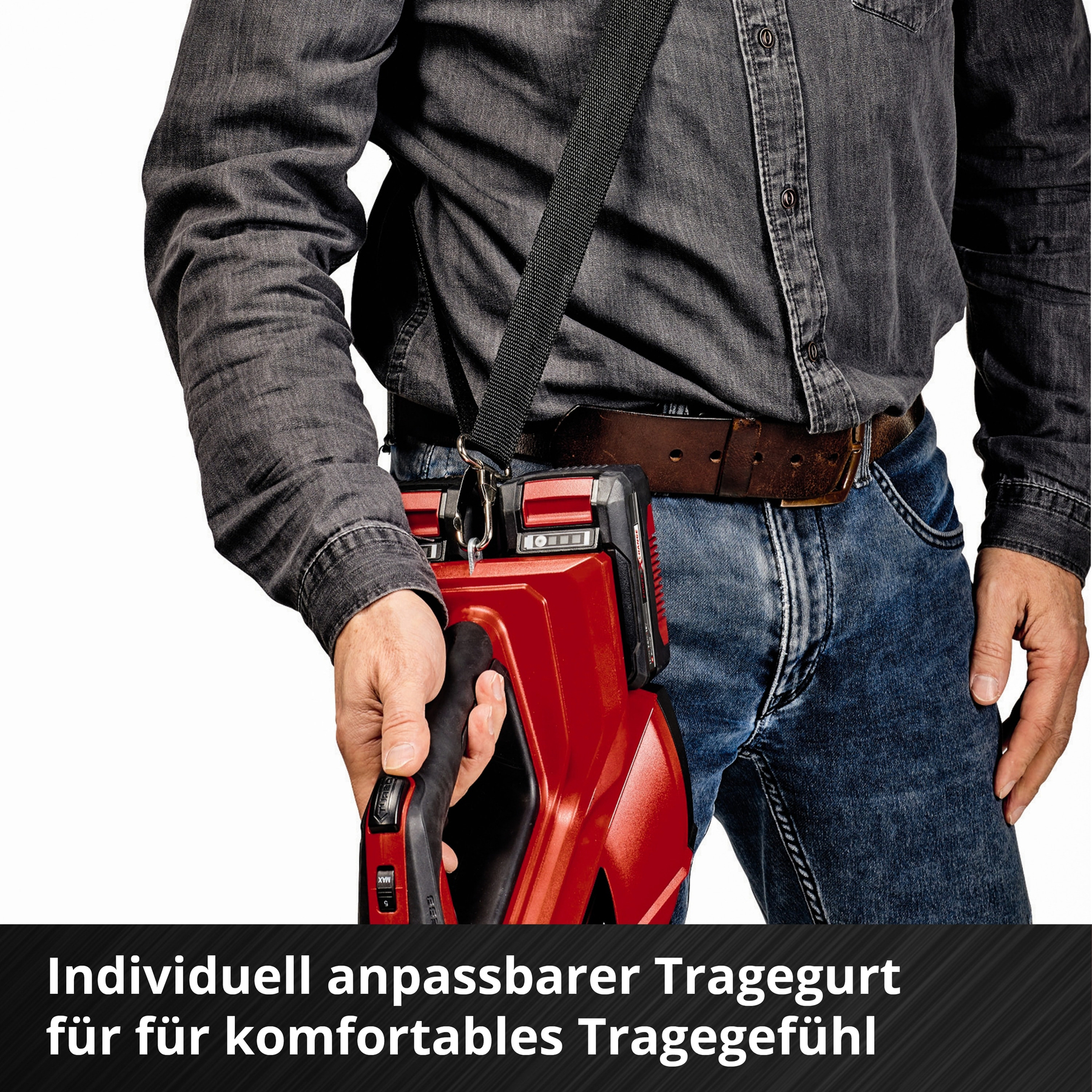 Eine Person, die ein rotes Werkzeug hält und ein graues Hemd und Jeans trägt. Das Werkzeug hat einen schwarzen Schultergurt.