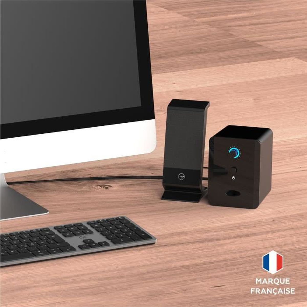 Un'installazione computer con monitor, tastiera e altoparlanti su una scrivania di legno. Gli altoparlanti sono neri con luce blu.