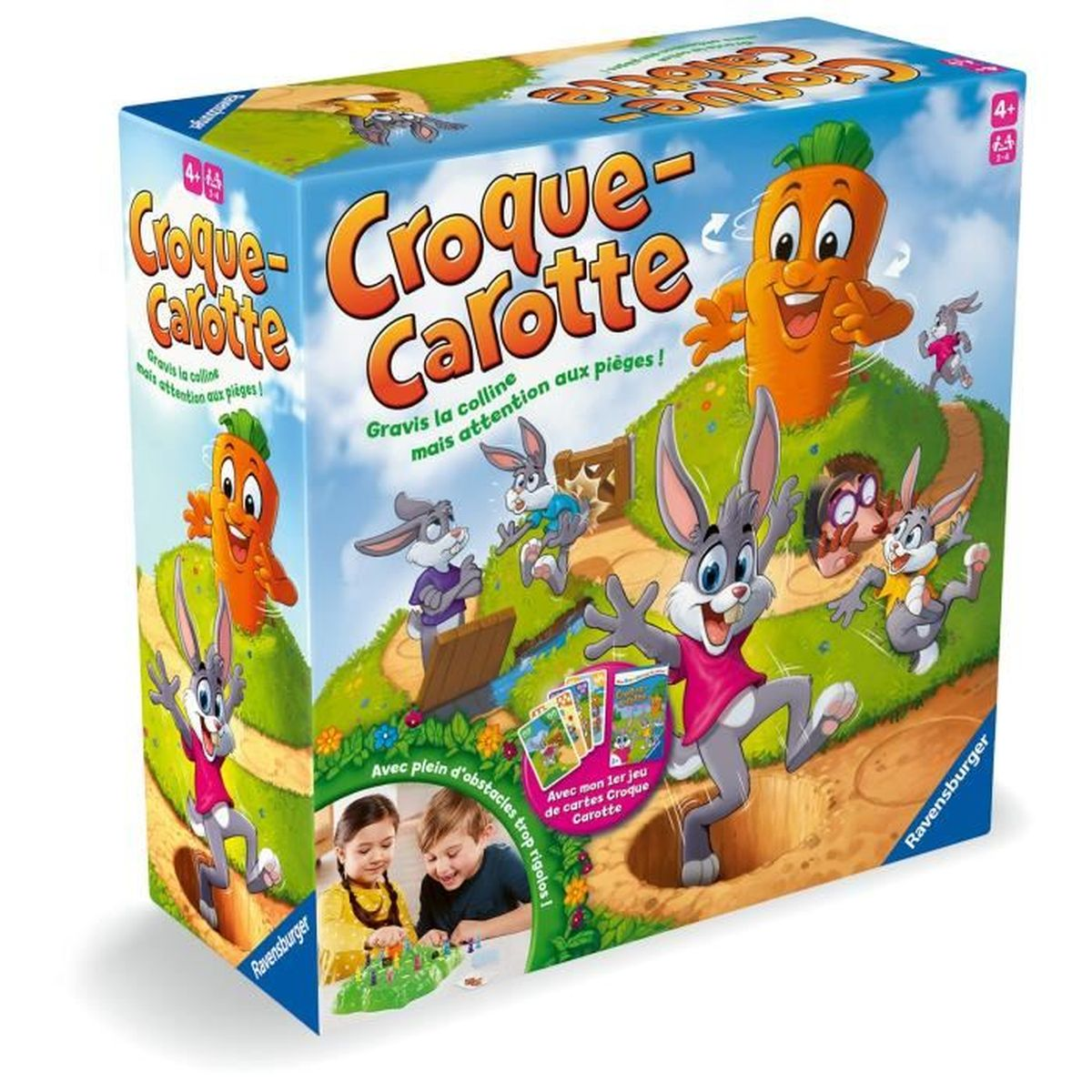 Schachtel des Spiels Croque-Carotte mit Kaninchen und Karotte. Kinder spielen mit dem Spiel. Der Hintergrund ist ein grüner Hügel.