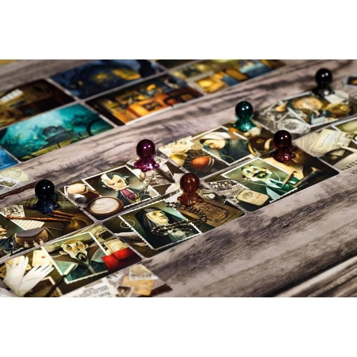 Brettspiel im Gange. Karten mit Charakteren und Objekten liegen auf einer Holzoberfläche. Farbige Spielfiguren sind auf den Karten platziert.
