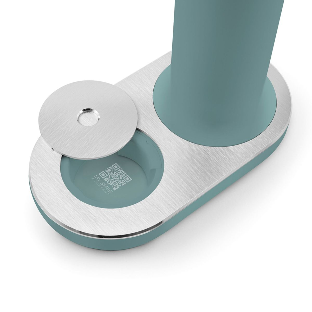 Ein türkis-silbernes Gerät mit zylindrischem Sockel und rundem Deckel. Ein QR-Code ist in einer runden Vertiefung sichtbar.