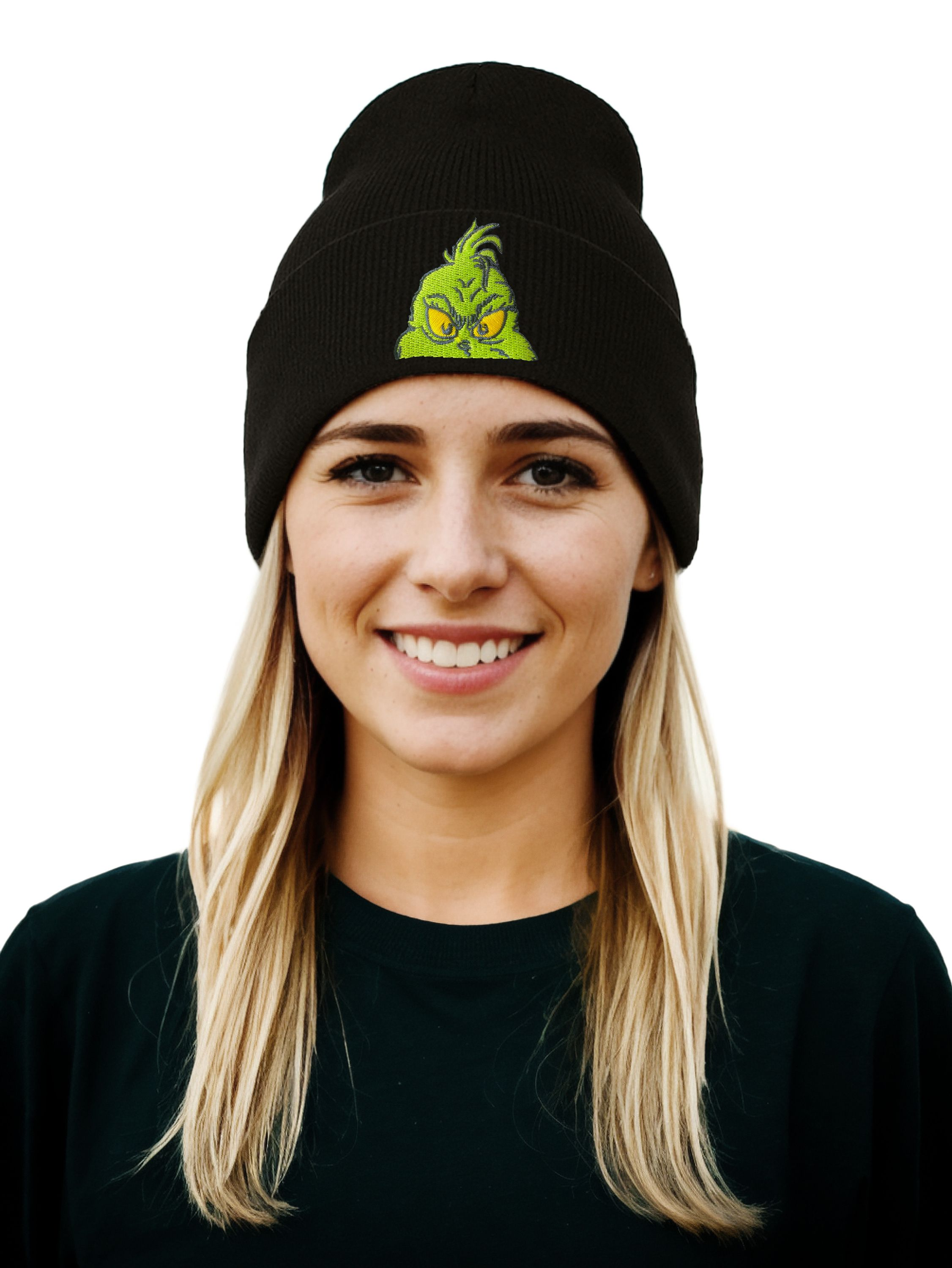 Eine lächelnde Frau mit einer schwarzen Mütze mit Grinch-Design. Sie hat blondes Haar und ein schwarzes Hemd.