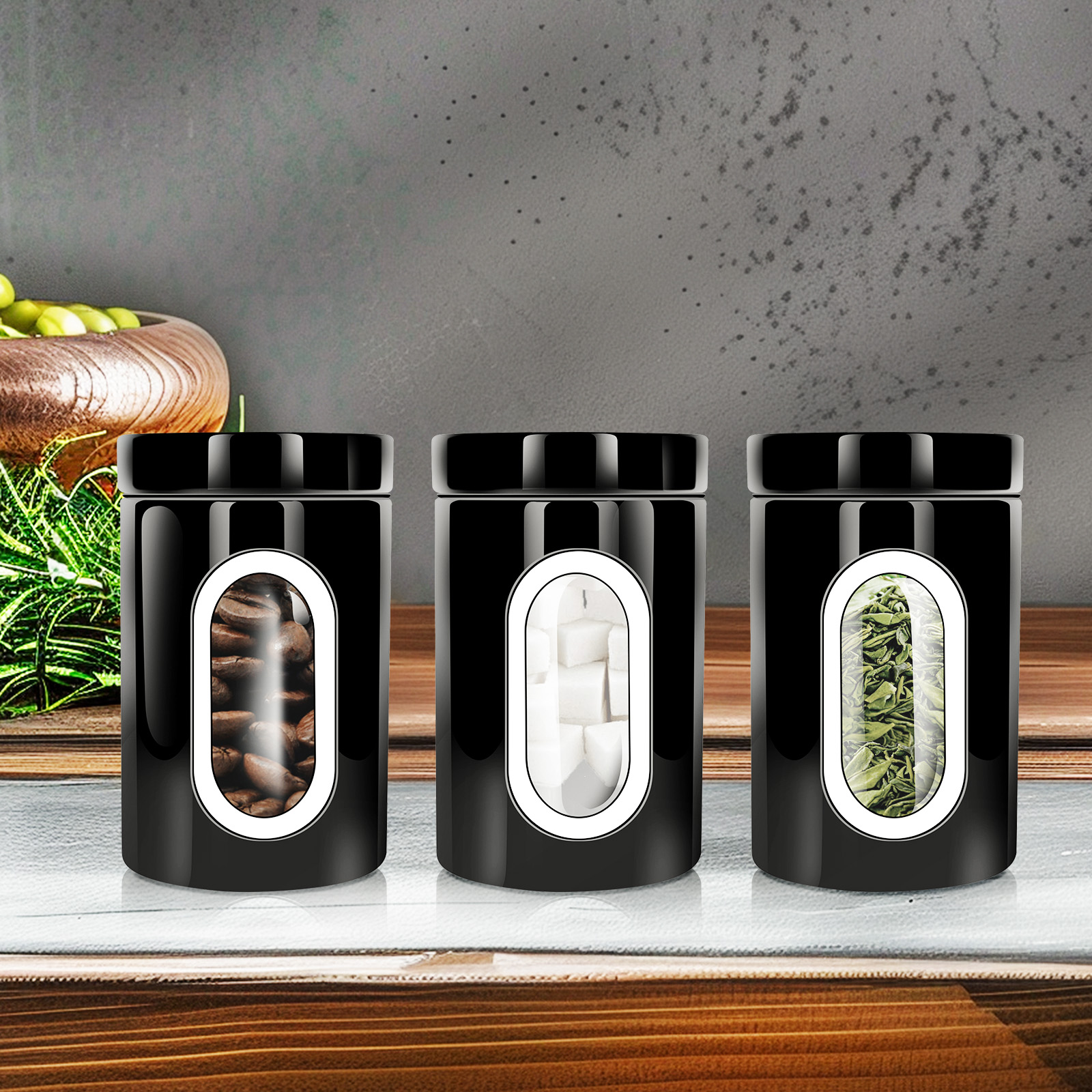 Drei schwarze Gläser mit Kaffeebohnen, Zuckerwürfeln und Teeblättern auf einer Holzoberfläche. Im Hintergrund eine Schüssel mit Oliven.