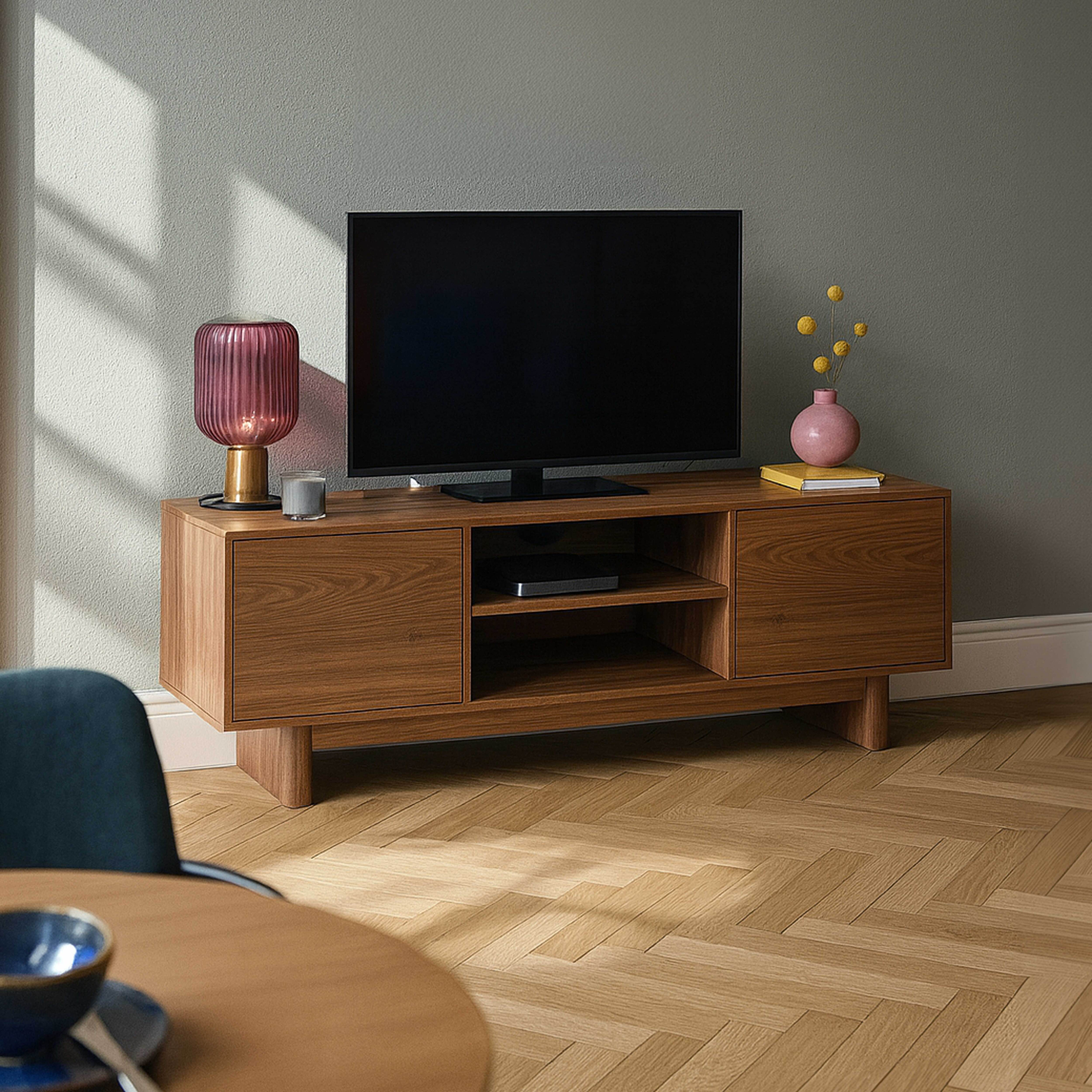 TV-Ständer aus Holz mit TV, Lampe und Deko. Holzboden. Graue Wand mit Schatten. Runder Tisch mit Schüssel.
