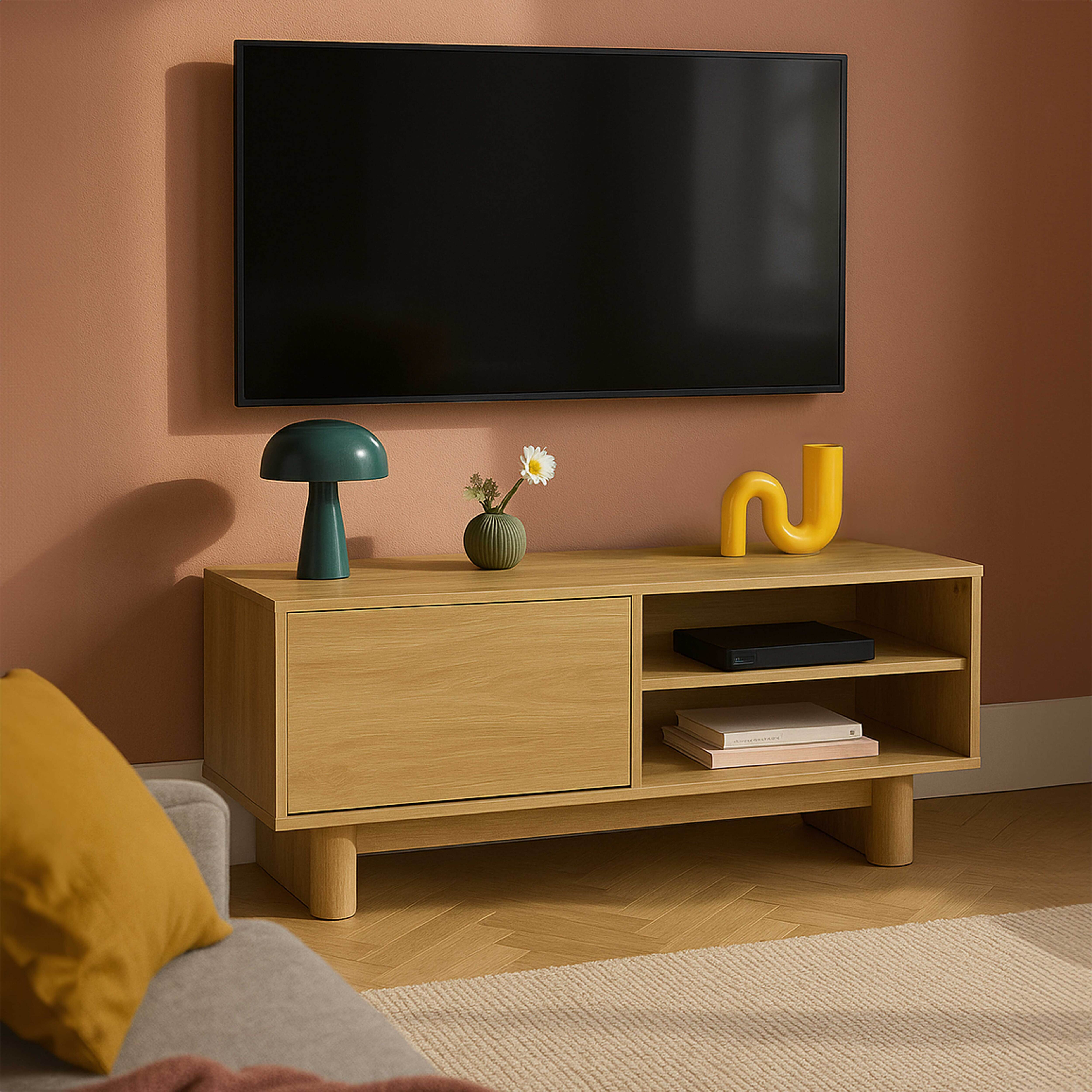 Ein Fernseher über einem Holzschrank mit Dekorationen und einem Sofa mit gelbem Kissen.